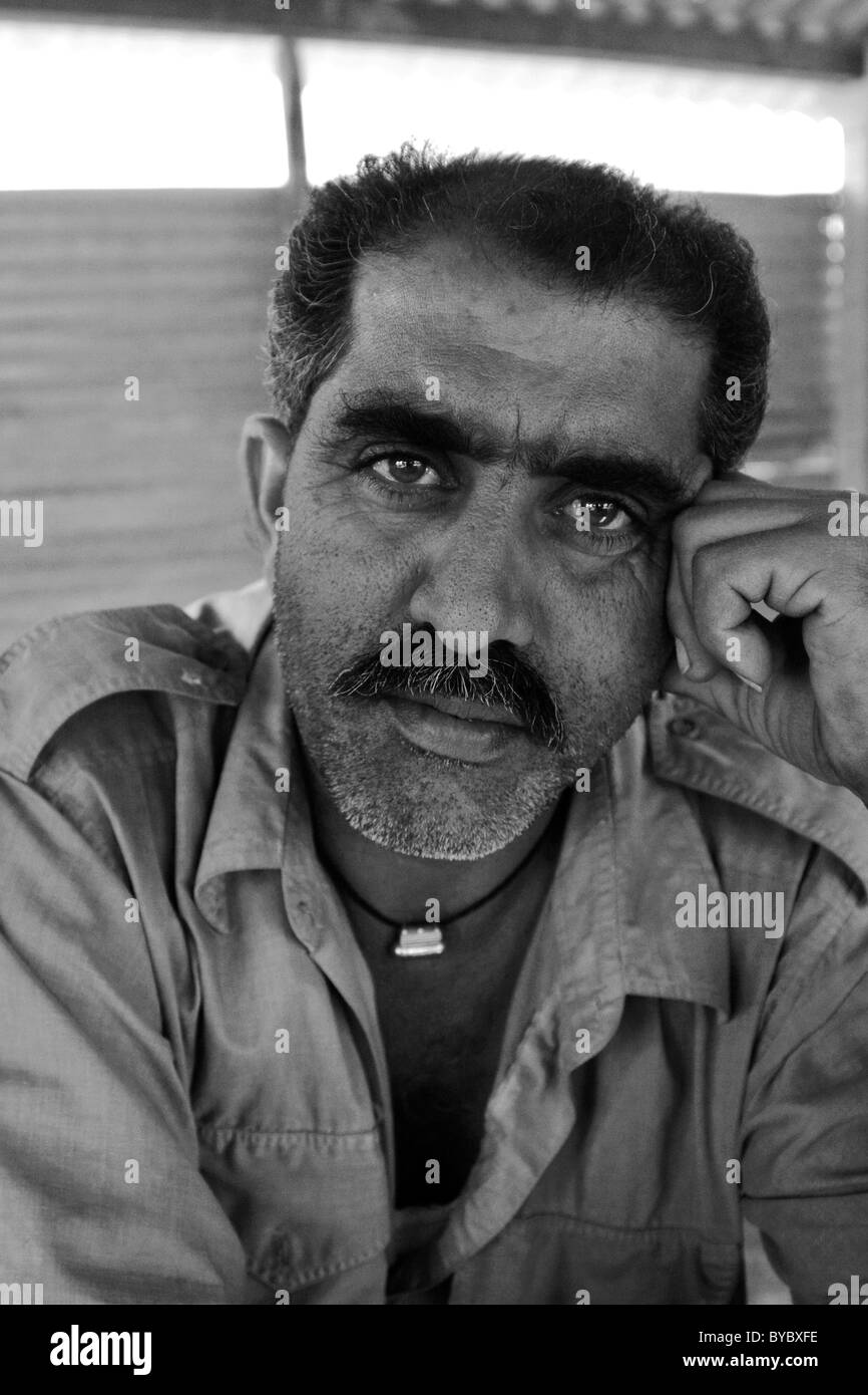 Bus-Driver ressemble attentivement tout en tenant l'appareil photo à son travail-rupture de l'État du Gujarat, en Inde. Noir et blanc. Banque D'Images