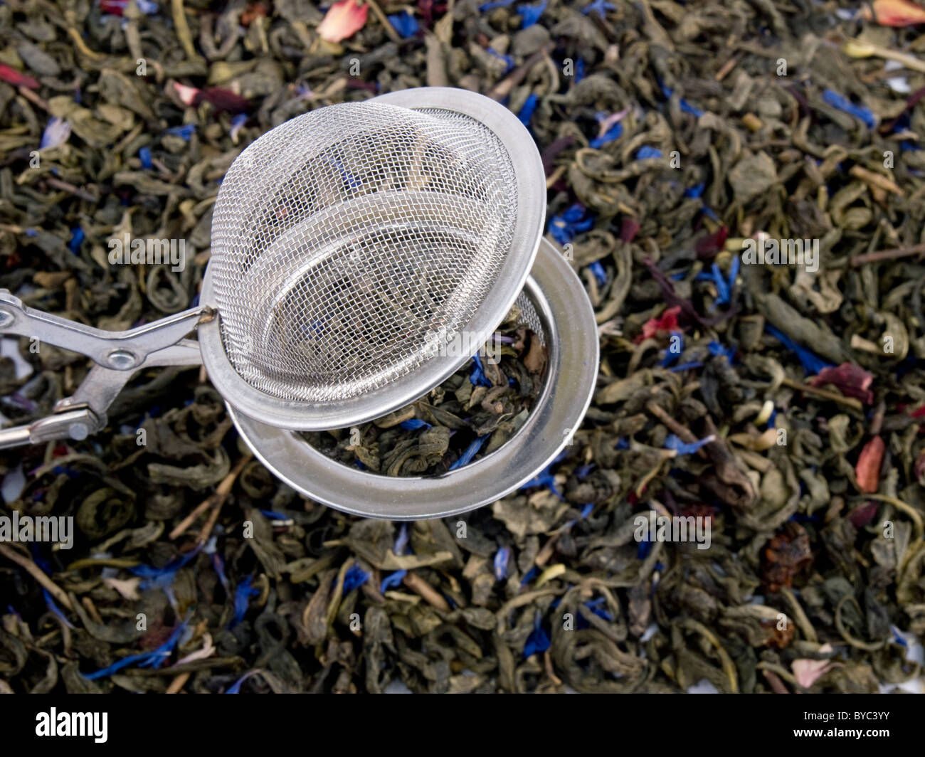 Boule à thé métal et feuilles de thé vert aromatiques Banque D'Images