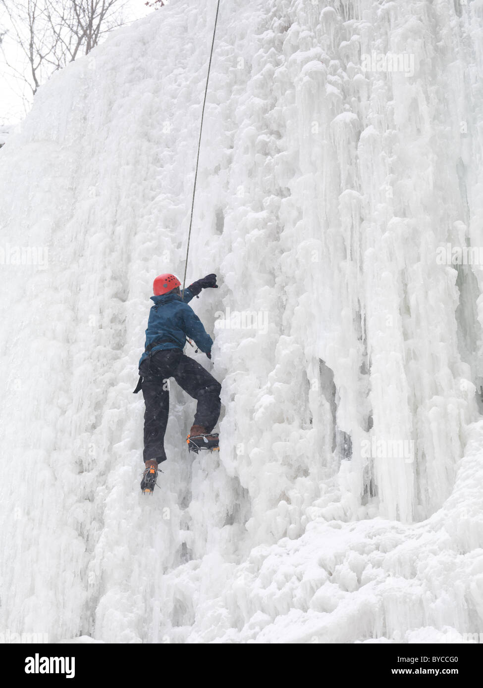 Grimpeur sur glace escalade d'une cascade gelée. Hiver scenic, l'Ontario, Canada. Banque D'Images