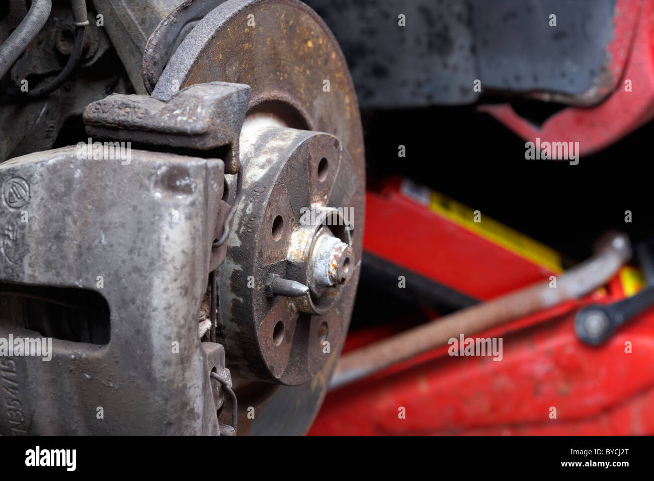 Disque de frein avant old rusty voiture sur un cric rouleur pour maintenance Banque D'Images