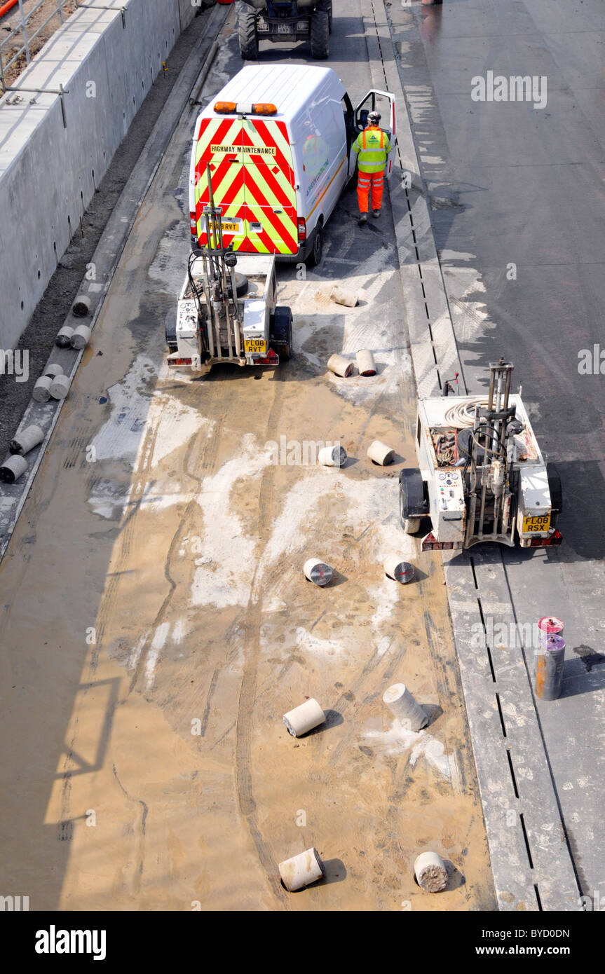 L'équipement de forage de béton dans les trous formant barrière pour l'écrasement de la route au cours de projet d'élargissement autoroute M25 Banque D'Images