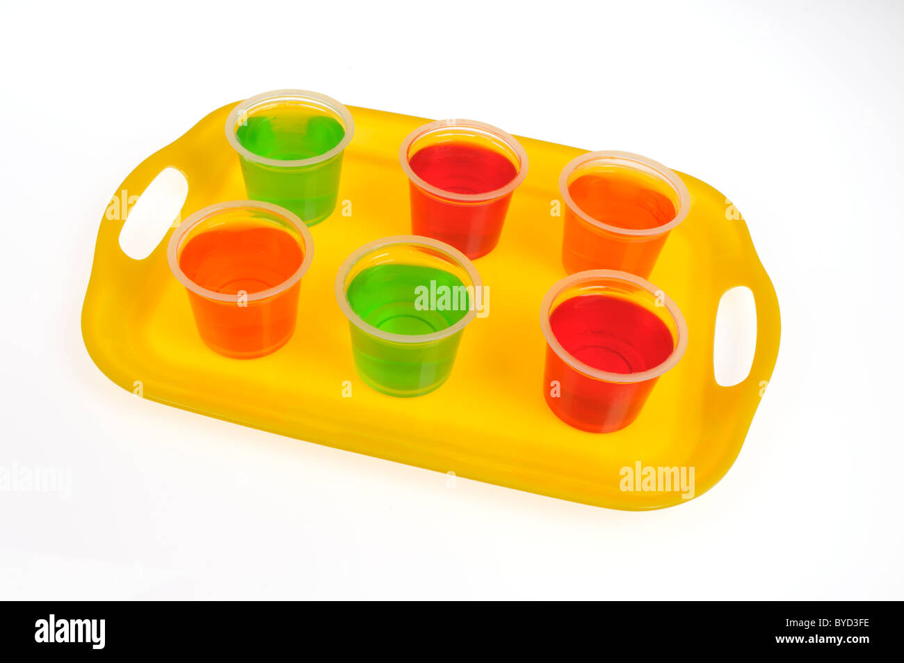 Pots colorés de Jell-O sur le bac jaune sur fond blanc Banque D'Images Pots colorés de Jell-O sur le bac jaune sur fond blanc Banque D'Images