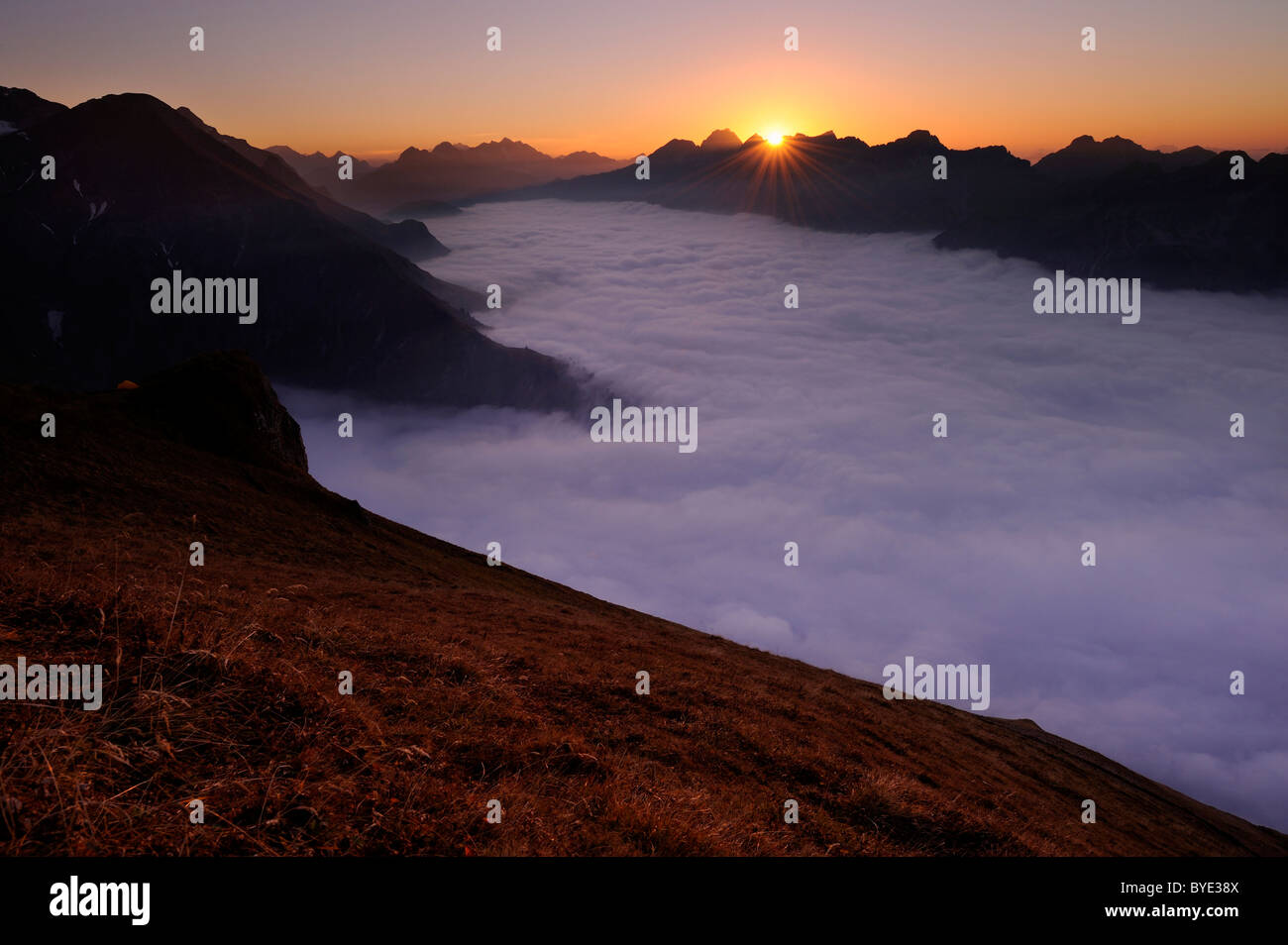 Mountain Valley sous le brouillard avec des pics de montagne dans la lumière du soir, Alpes Allgaeu, vallée de Kleinwalsertal, Vorarlberg, Autriche Banque D'Images