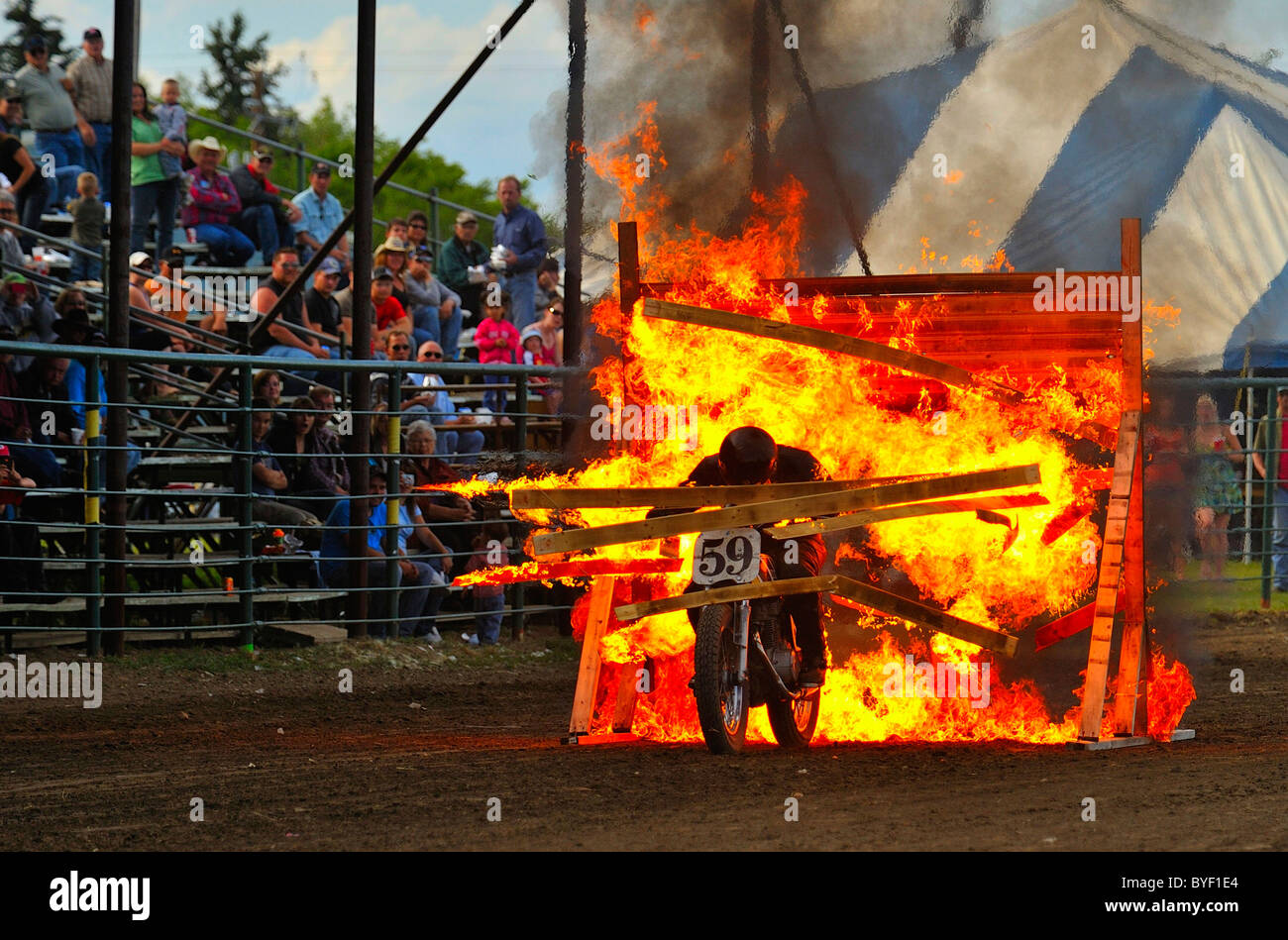 Un pilote de motocross se plante à travers une barrière en bois Banque D'Images
