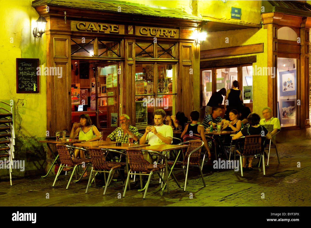Les gens de l'extérieur d'un café à Annecy dans la nuit Banque D'Images