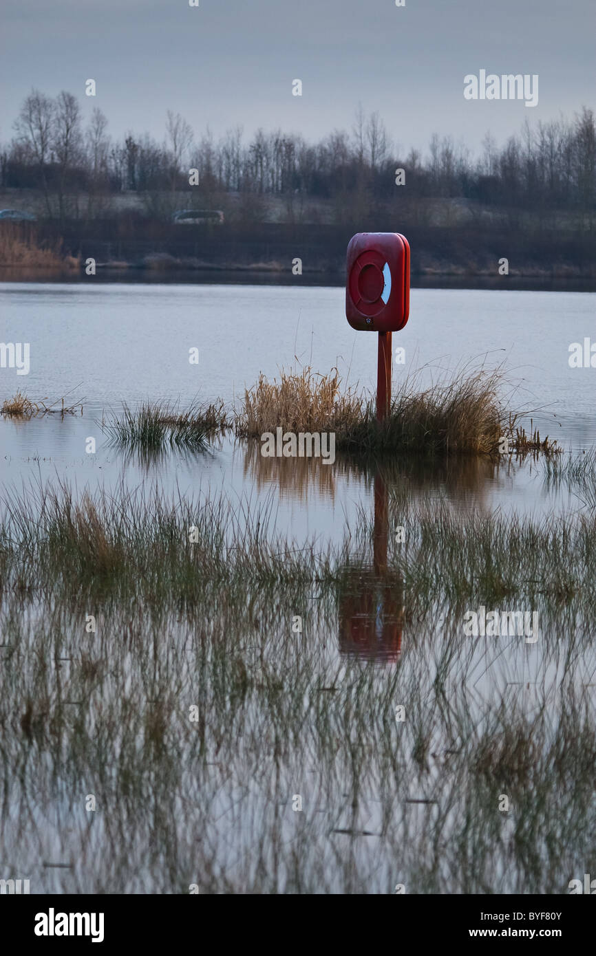 Un anneau de sauvetage par l'berges inondées d'un lac Banque D'Images