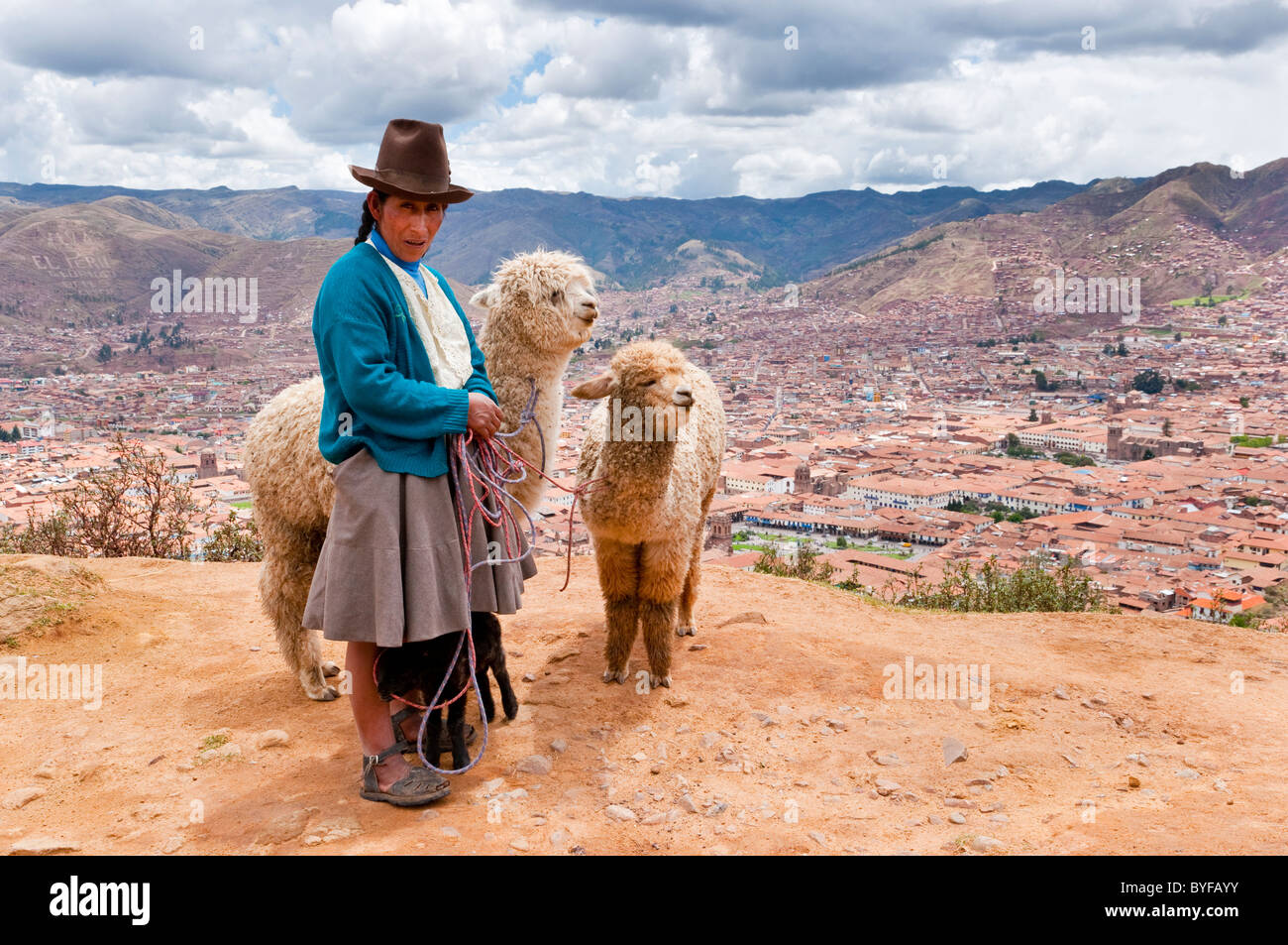 Une dame péruvienne en costume traditionnel avec ses lamas surplombant la ville de Cusco, Pérou, Amérique du Sud. Banque D'Images