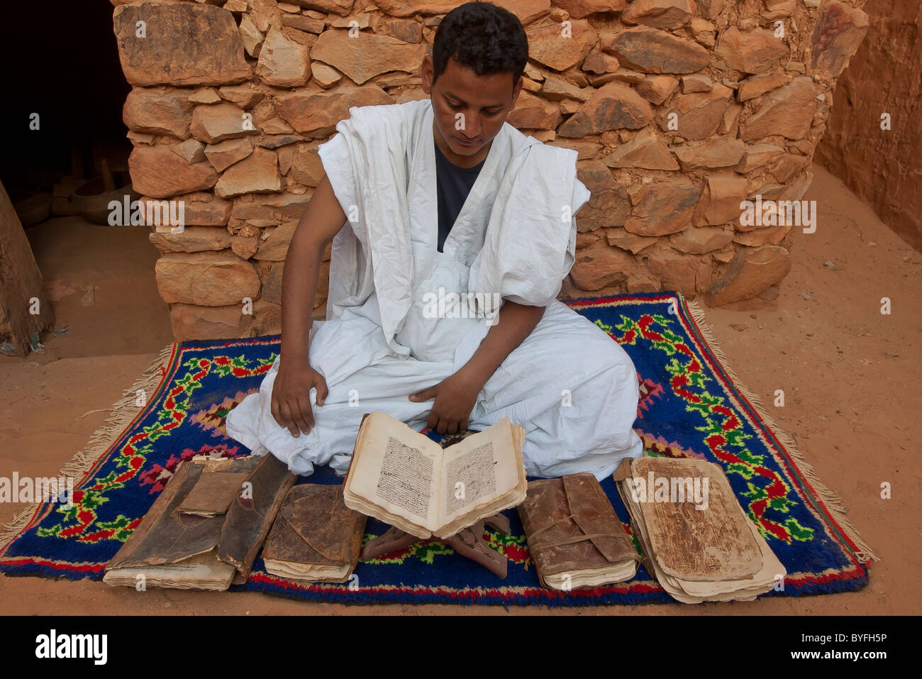 Garçon arabe lecture textes coraniques de livres anciens à Chinguetti, Mauritanie, du site d'une des plus anciennes du monde mosquées Banque D'Images