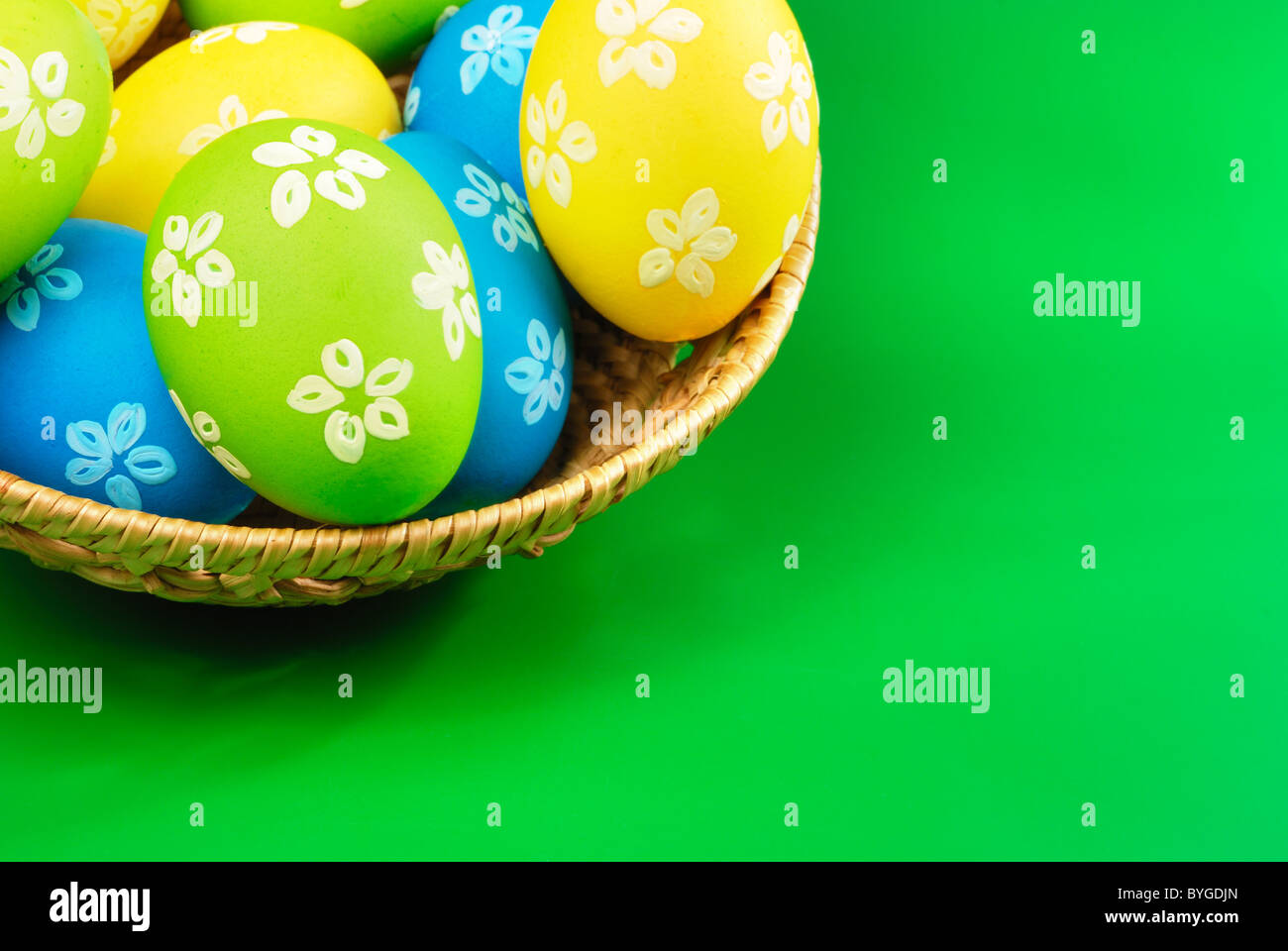 Oeufs de Pâques en panier en osier sur fond vert Banque D'Images