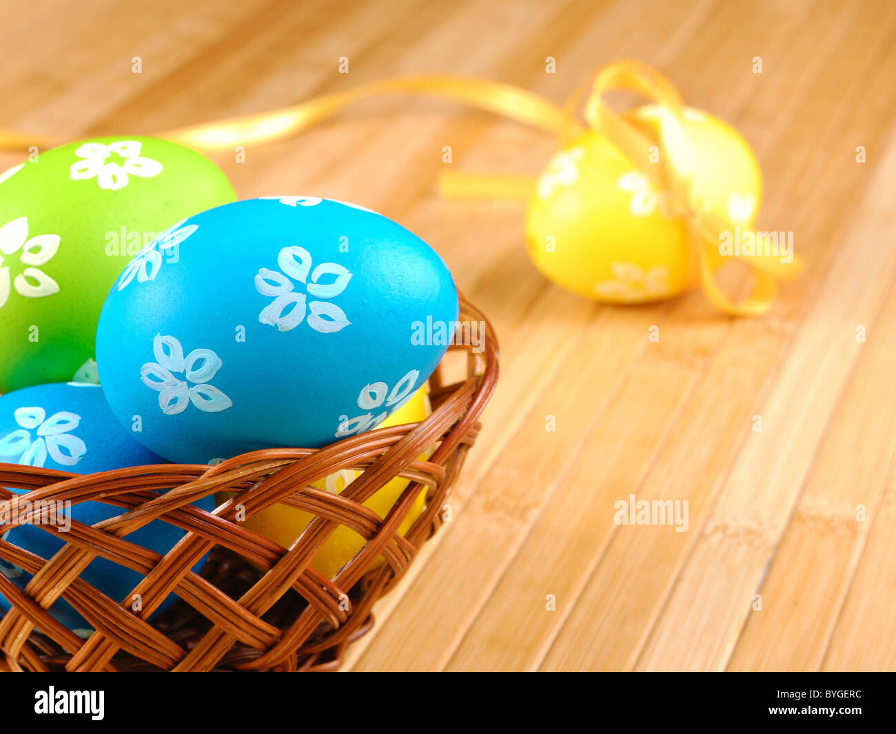 Oeufs de Pâques en panier en osier sur la table en bois Banque D'Images