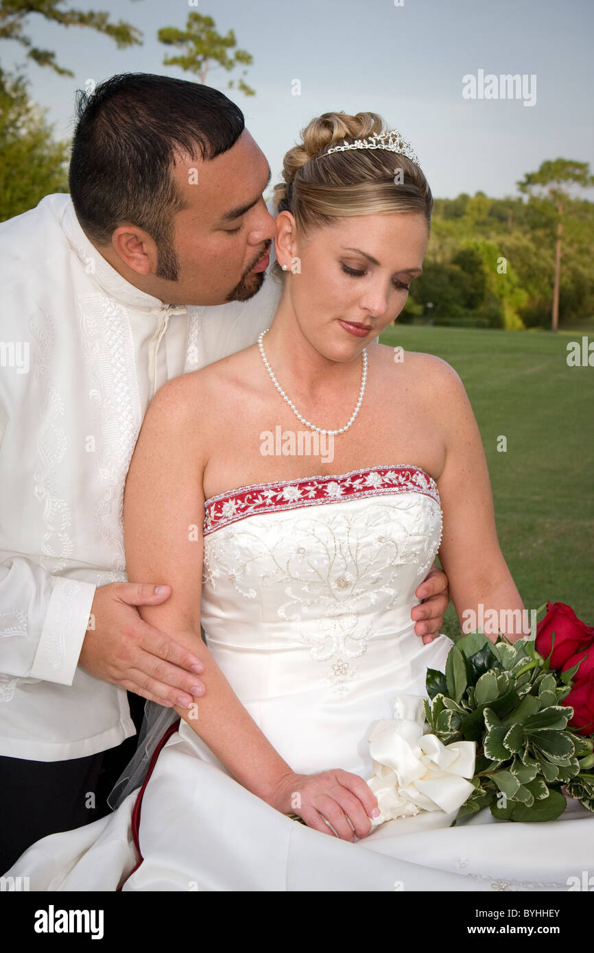 Mariée et le marié romantique partager une tendre étreinte sur l'herbe pendant une pause à la réception. Banque D'Images