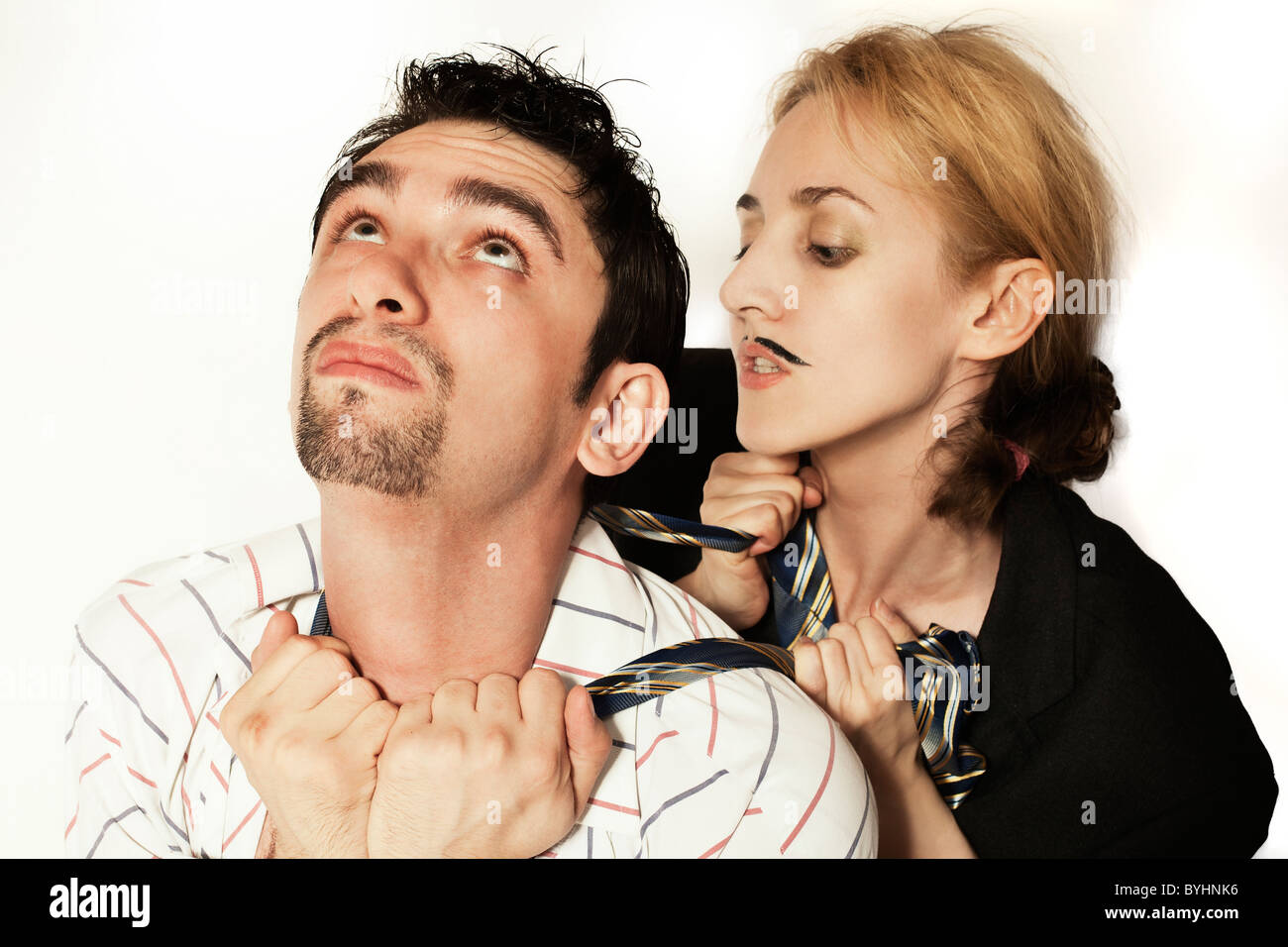 Femme avec une moustache artificielle d'étrangler un jeune homme cravate sur fond blanc Banque D'Images