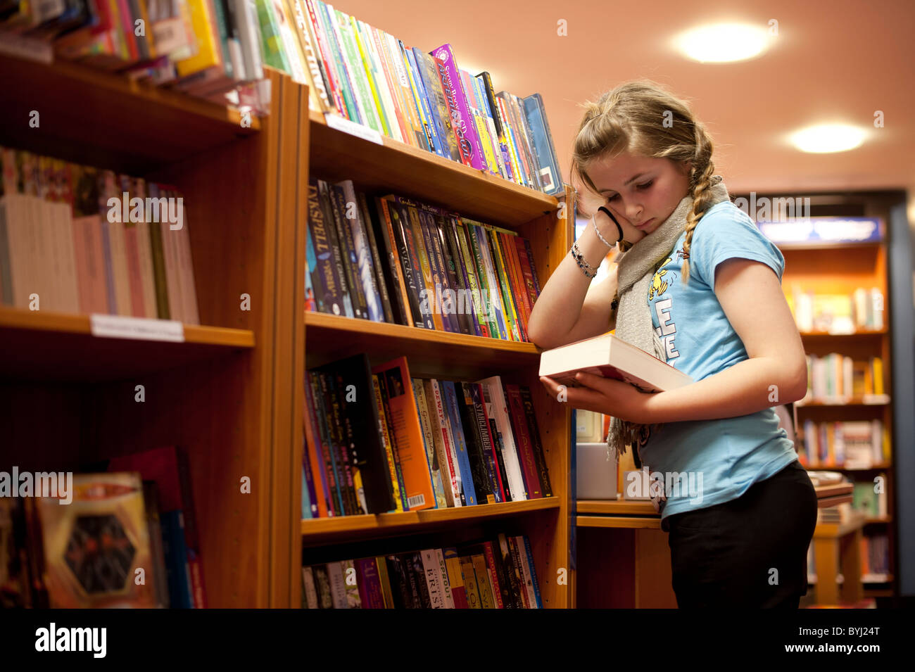 12 12 13 Un jeune de 14 ans teenage girl reading dans une librairie, UK Banque D'Images