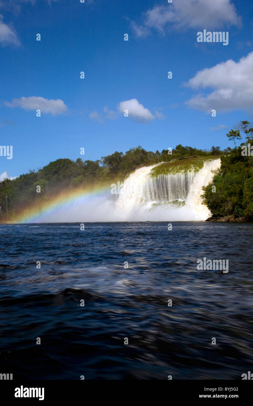 Photographie de Hacha cascade qui se termine au lac Canaima créant un effet arc-en-ciel de tournage sur une journée lumineuse avec ciel bleu Banque D'Images