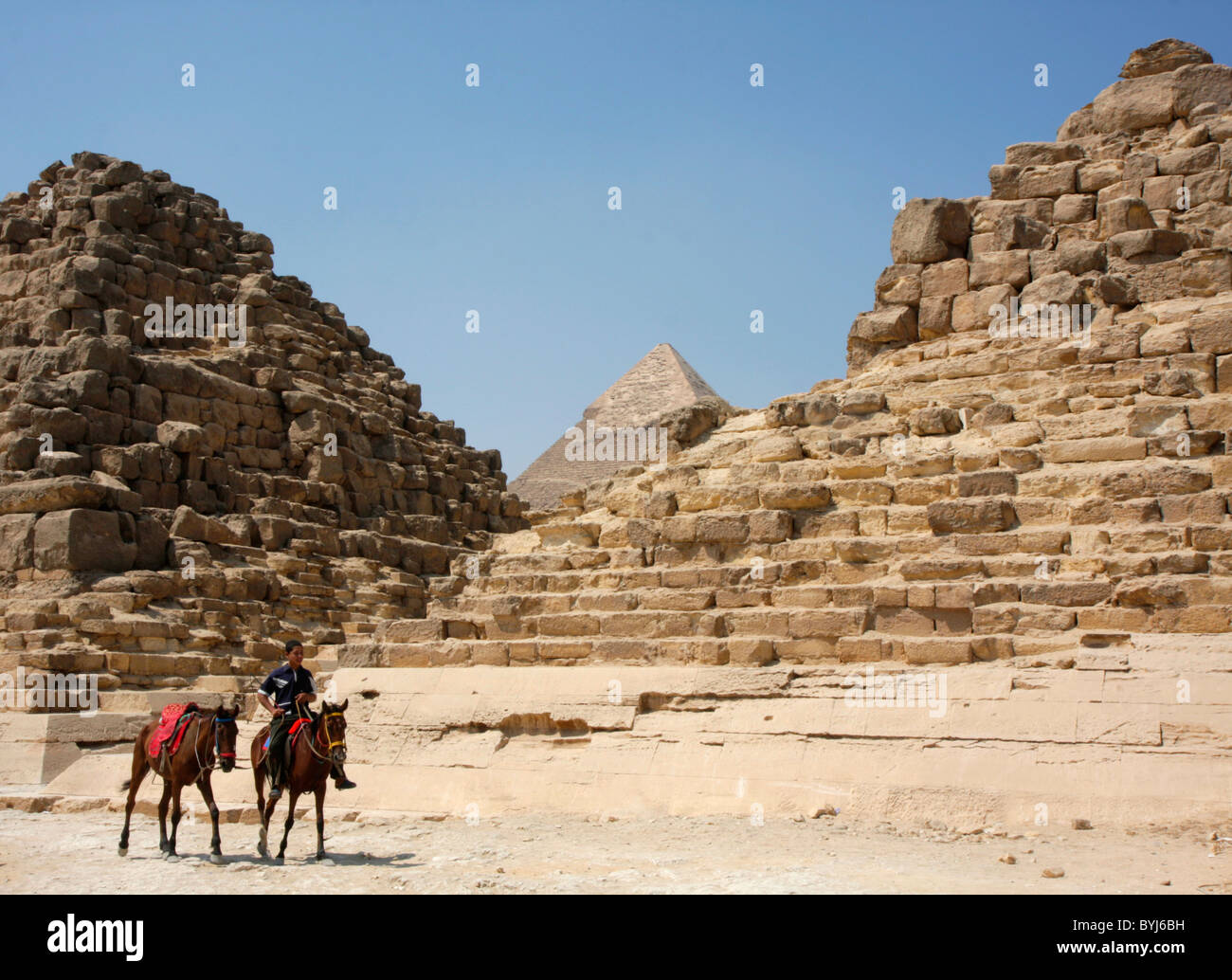 Un garçon égyptien monte un cheval, et mène un autre, en face des pyramides de Gizeh, Egypte. Banque D'Images