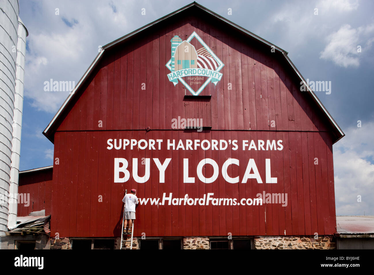 USA (Maryland), le comté de Harford, peintre d'enseignes professionnelles jusqu'touche logo Achat local sur le côté de la grange rouge le matin d'été Banque D'Images