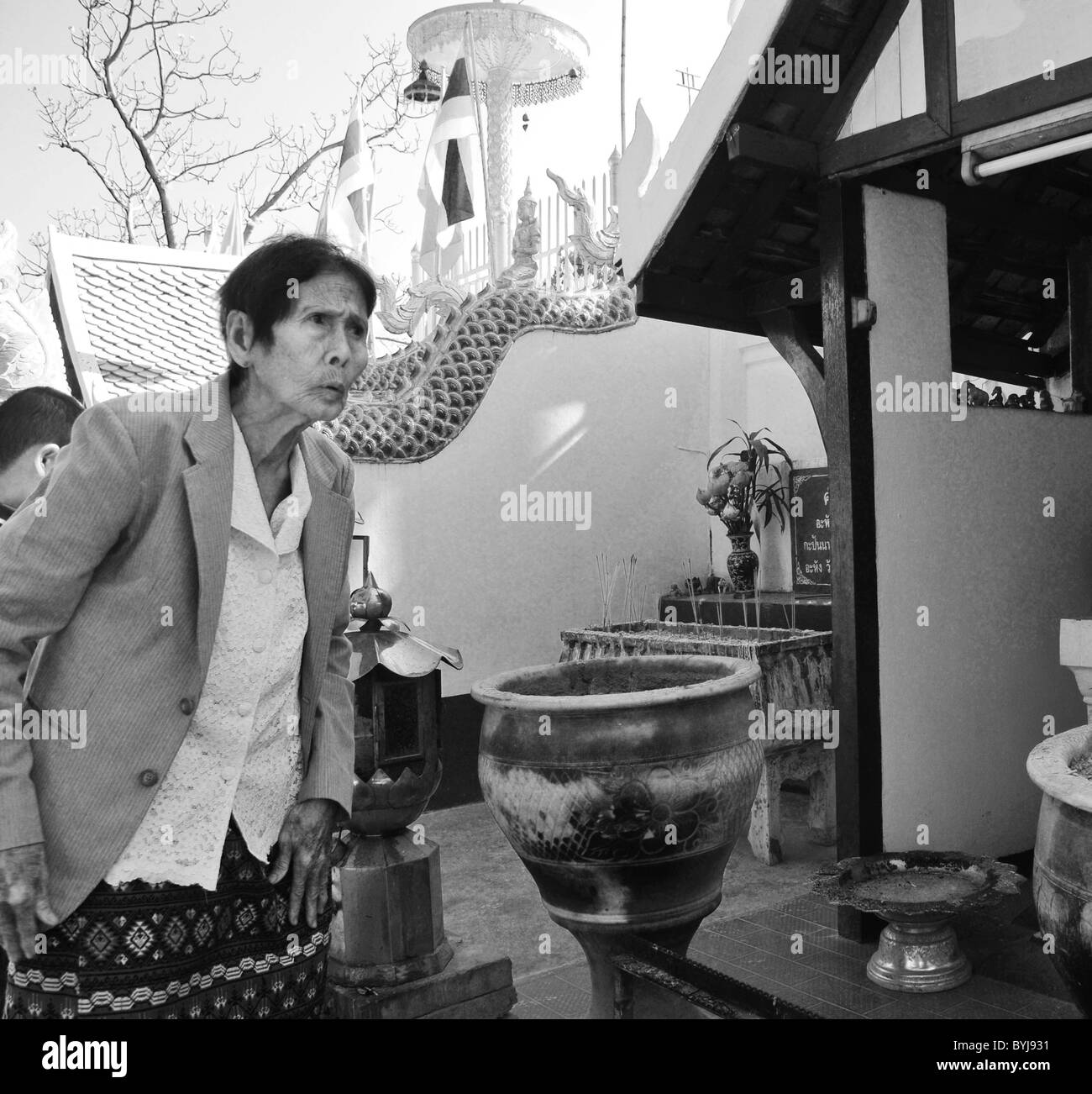Photographie en noir et blanc d'une vieille femme dans un temple thaïlandais Banque D'Images
