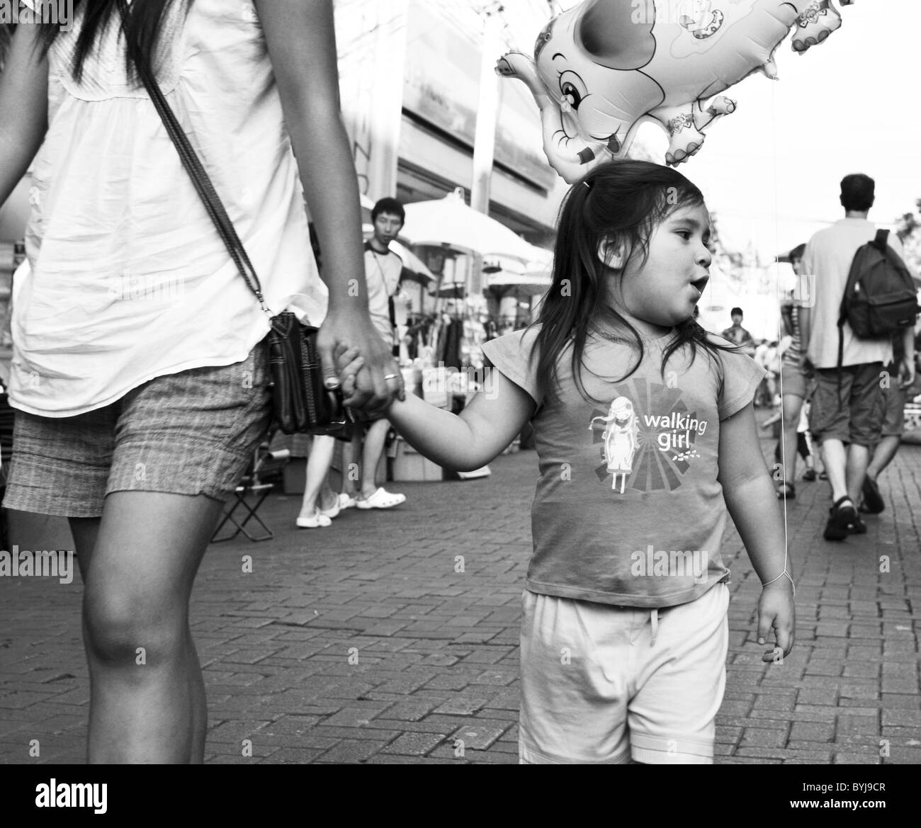 Photographie noir et blanc photographie candide d'une jeune fille thaïe dans une rue Banque D'Images