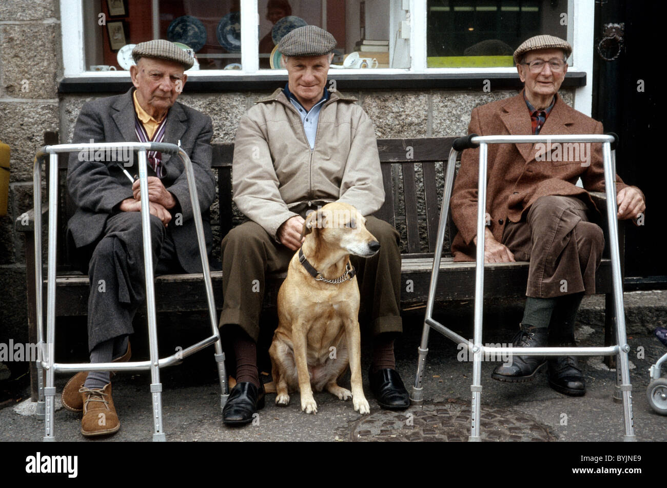 3 hommes âgés et un chien assis à l'extérieur avec zimmer frames Banque D'Images