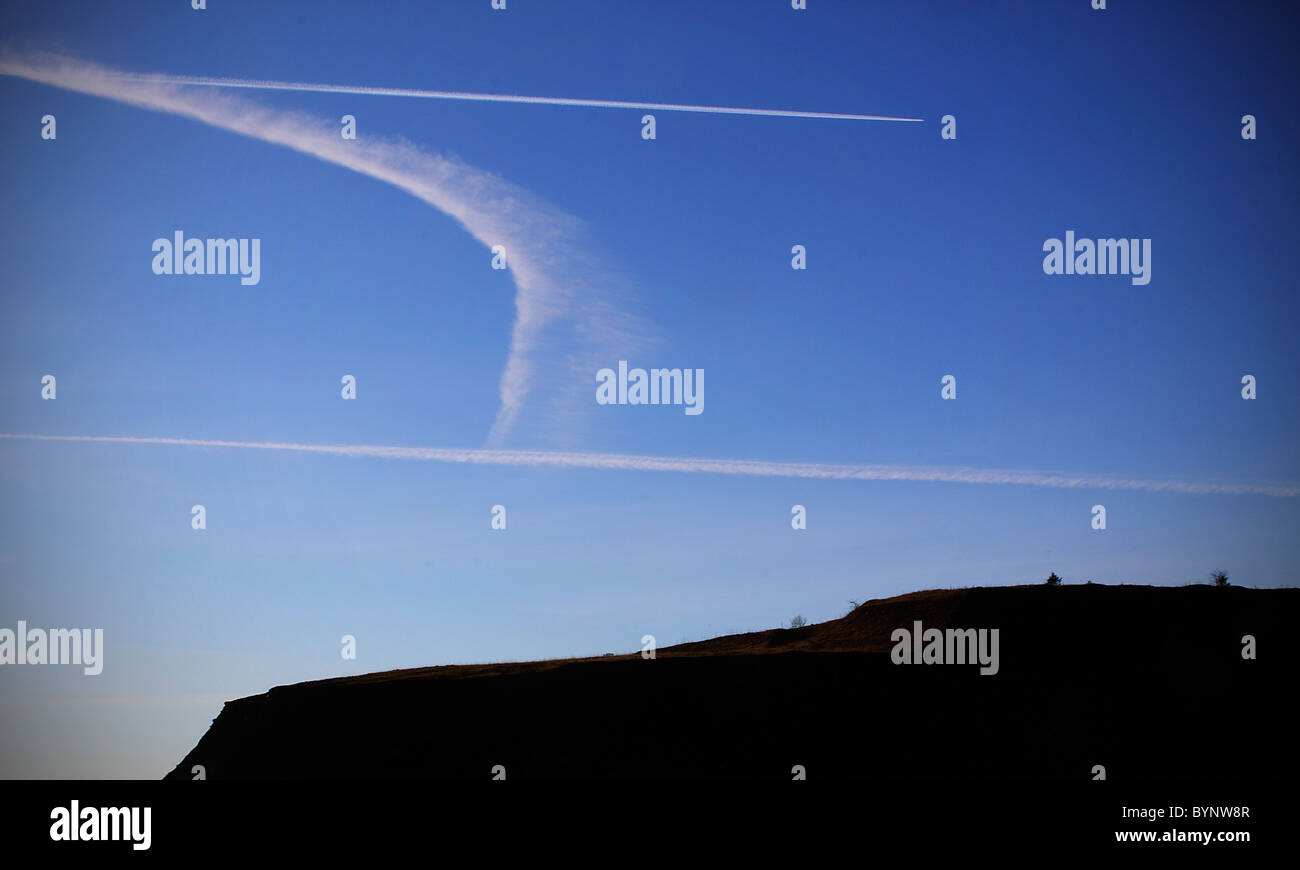 Streaky nuages contre un ciel bleu par-dessus le sommet d'une colline qui se profile Banque D'Images
