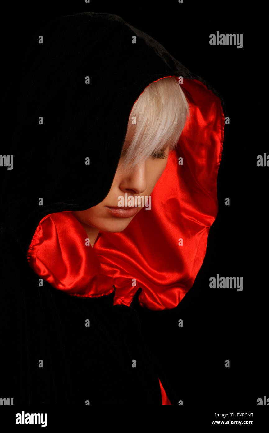 Jeune femme aux cheveux d'argent portant une cape noire bordée de rouge Banque D'Images