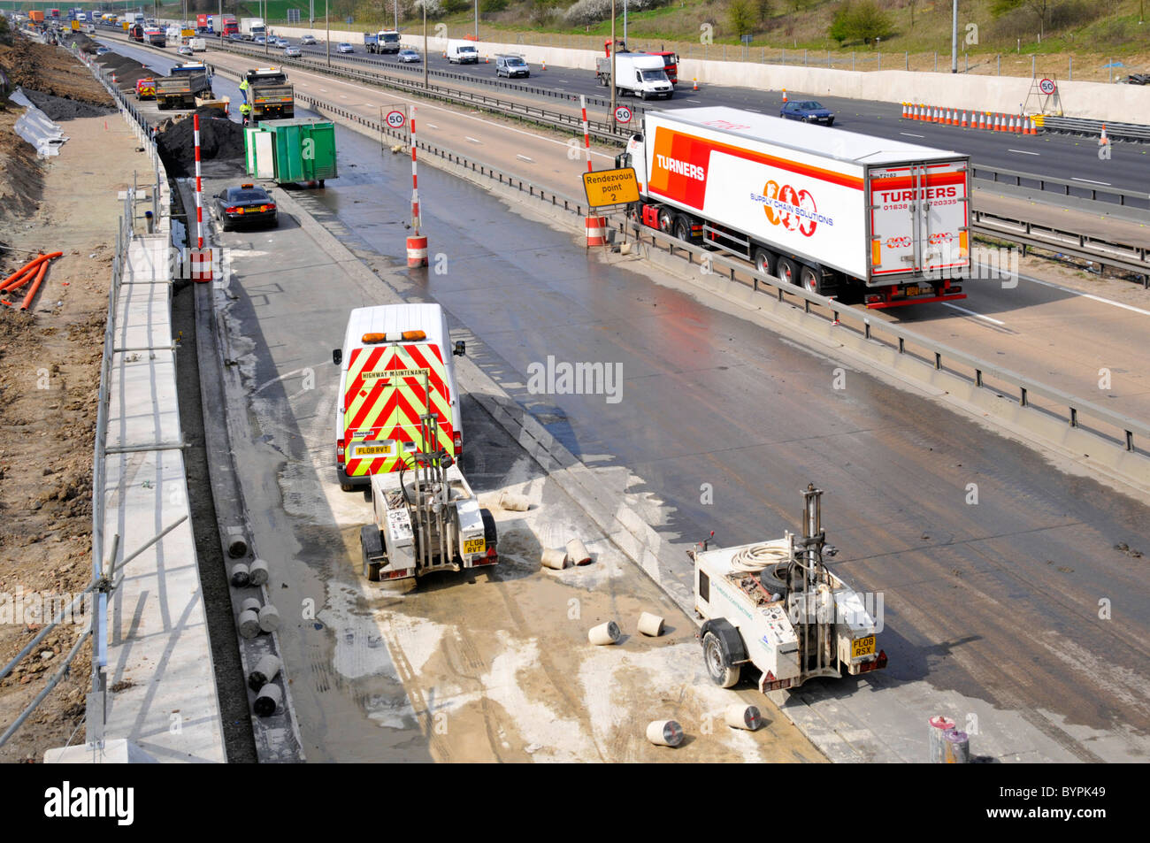 L'équipement de forage de béton dans les trous formant barrière pour l'écrasement de la route au cours de projet d'élargissement autoroute M25 Banque D'Images