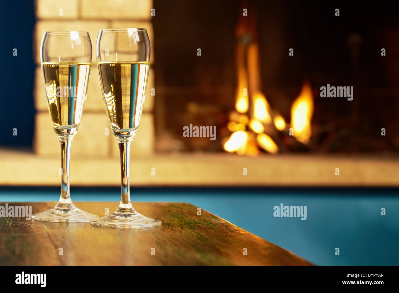 Libre de deux verres à vin avec du champagne sur la table et cheminée en arrière-plan. La forme horizontale Banque D'Images