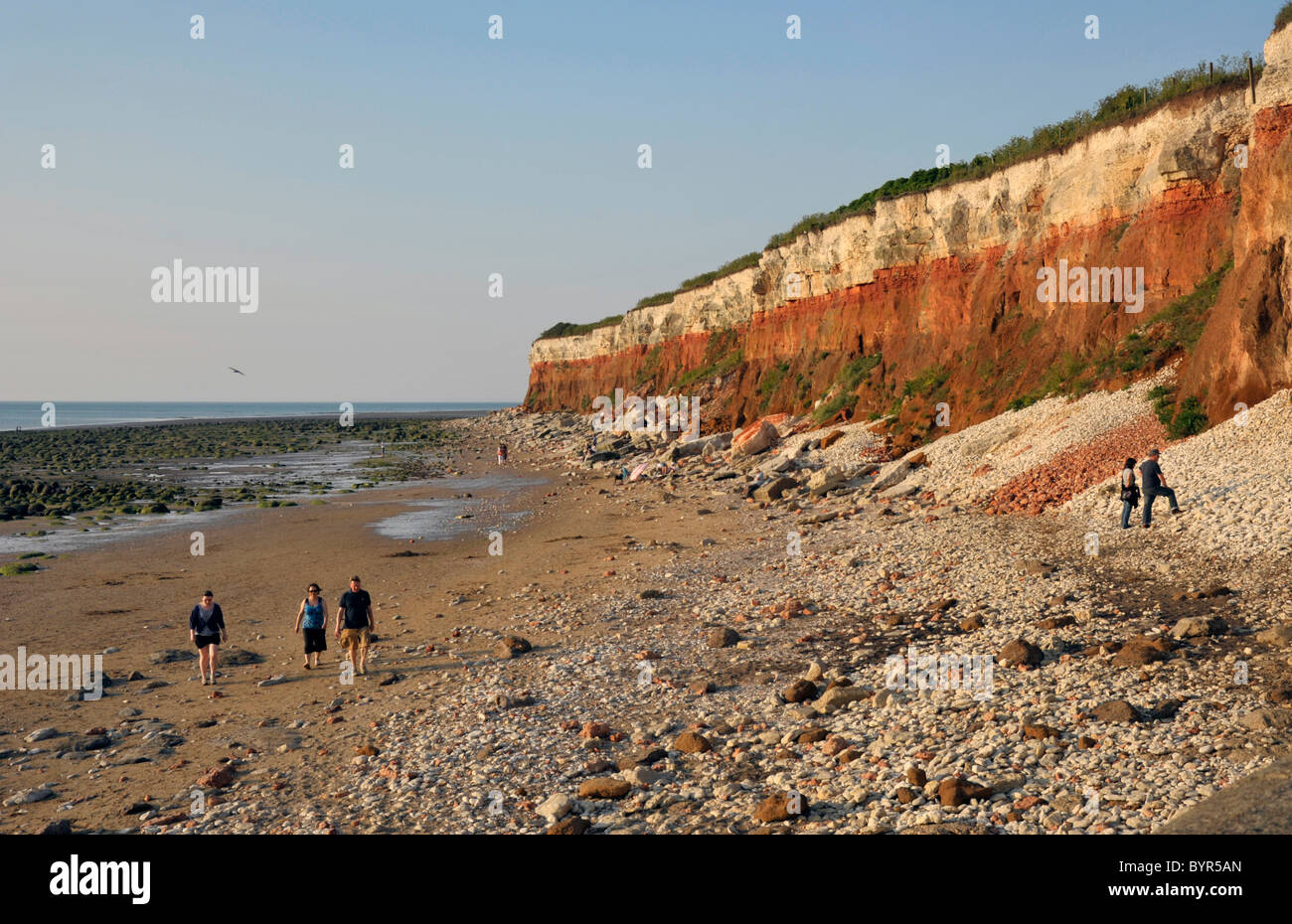 Les marcheurs à côté de rochers, à Hunstanton à Norfolk. Banque D'Images