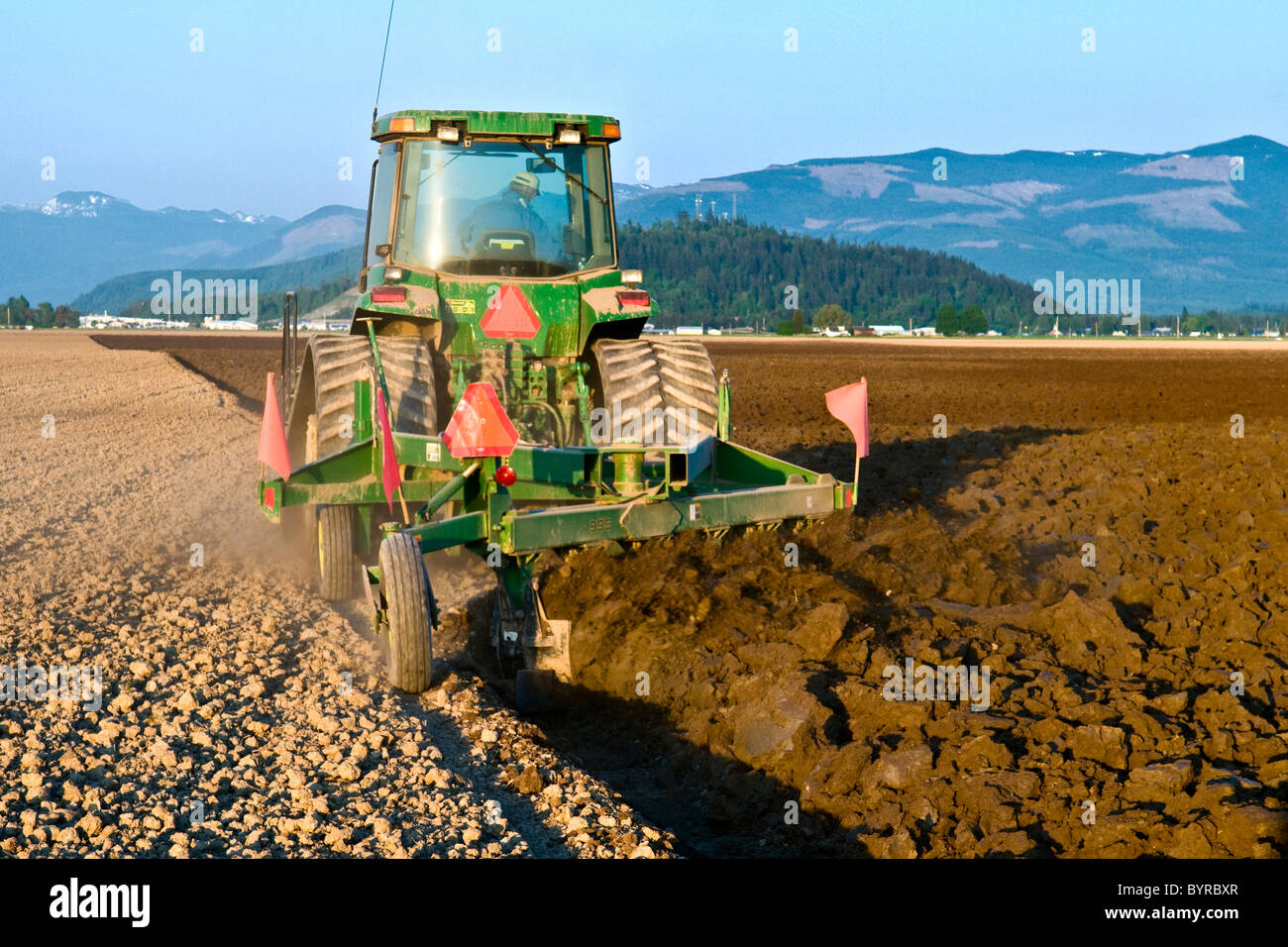 Un tracteur à chenilles John Deere tirant une charrue réversible prépare un champ pour la plantation de pommes de terre / près de Burlington, Vermont, USA Banque D'Images