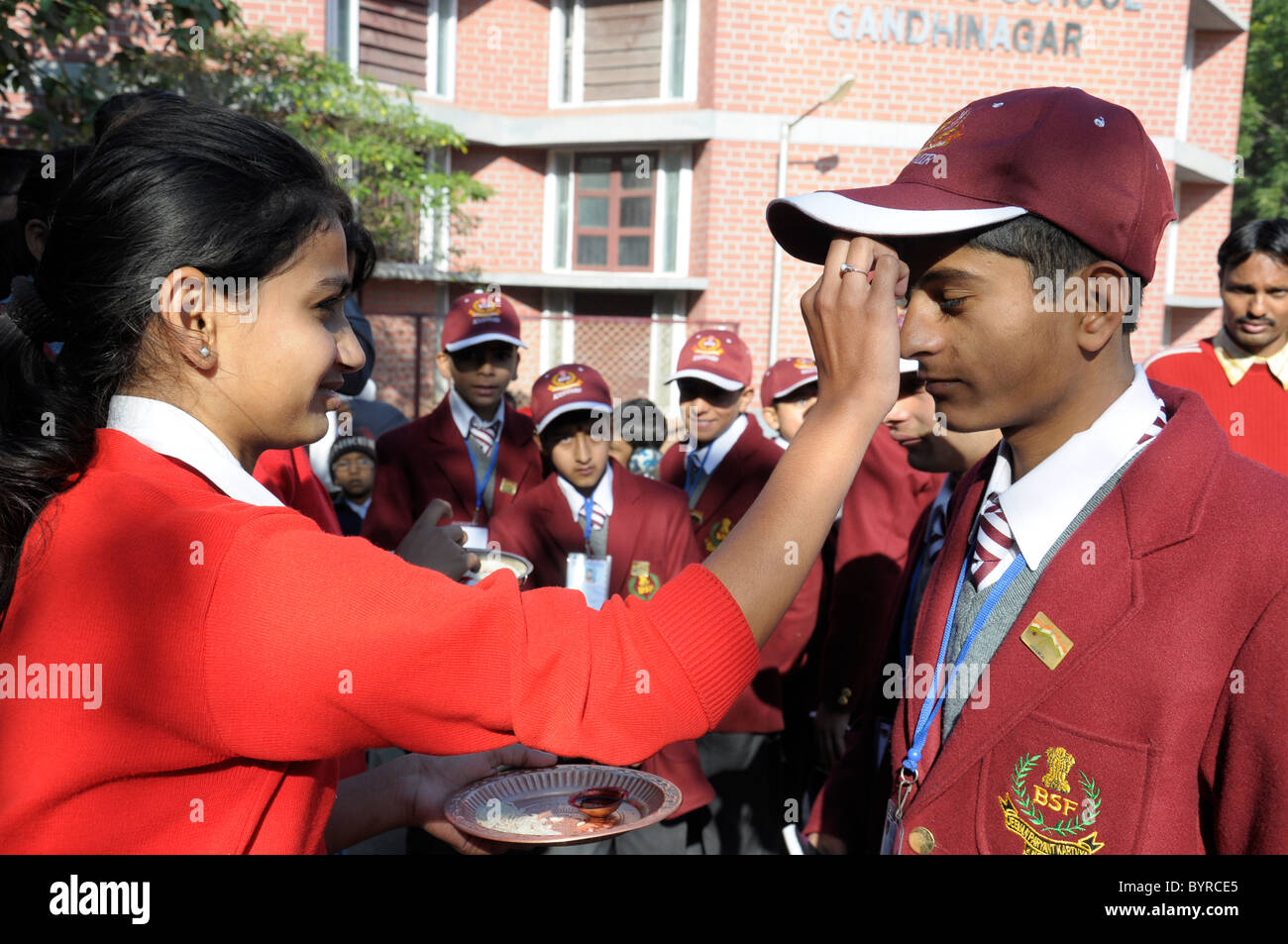Un étudiant filles appliquant tilak (marque rouge) sur le front d'un élève garçon à la veille de Raksha Bandhan, un festival en Inde Banque D'Images