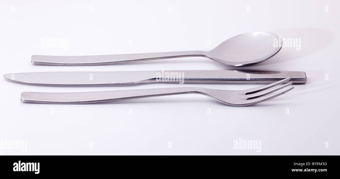 Le couteau fourchette et cuillère de conception modernes en acier inoxydable isolés contre le blanc et reflétant la lumière blanche Banque D'Images