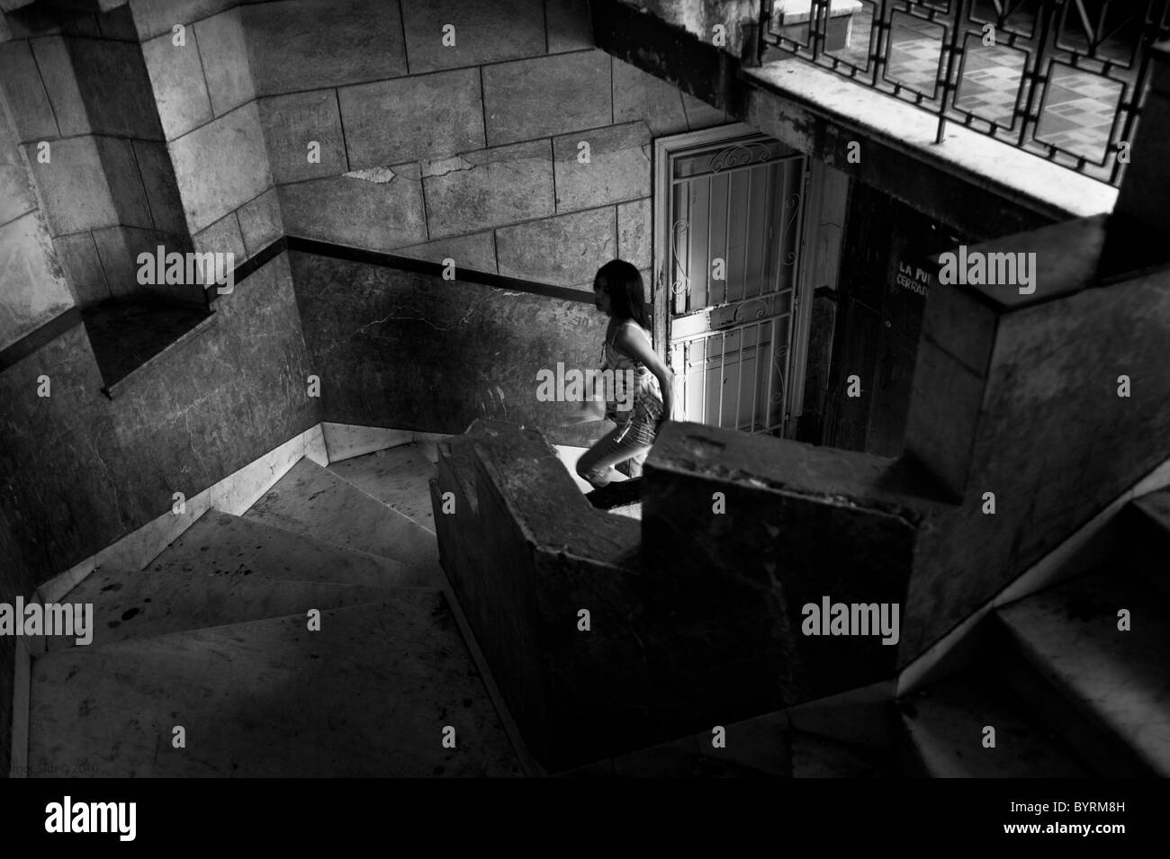 Une femme affirmant l'escalier sur une ancienne maison d'habitation à La Havane, Cuba Banque D'Images