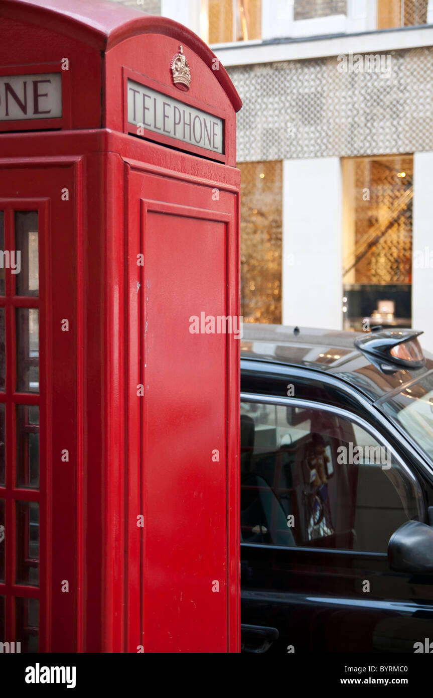 Cropped shot d'un rouge traditionnel avec phonebooth côté clair comme l'espace de copie à Londres, Royaume-Uni, avec black cab stationnée à proximité. Banque D'Images