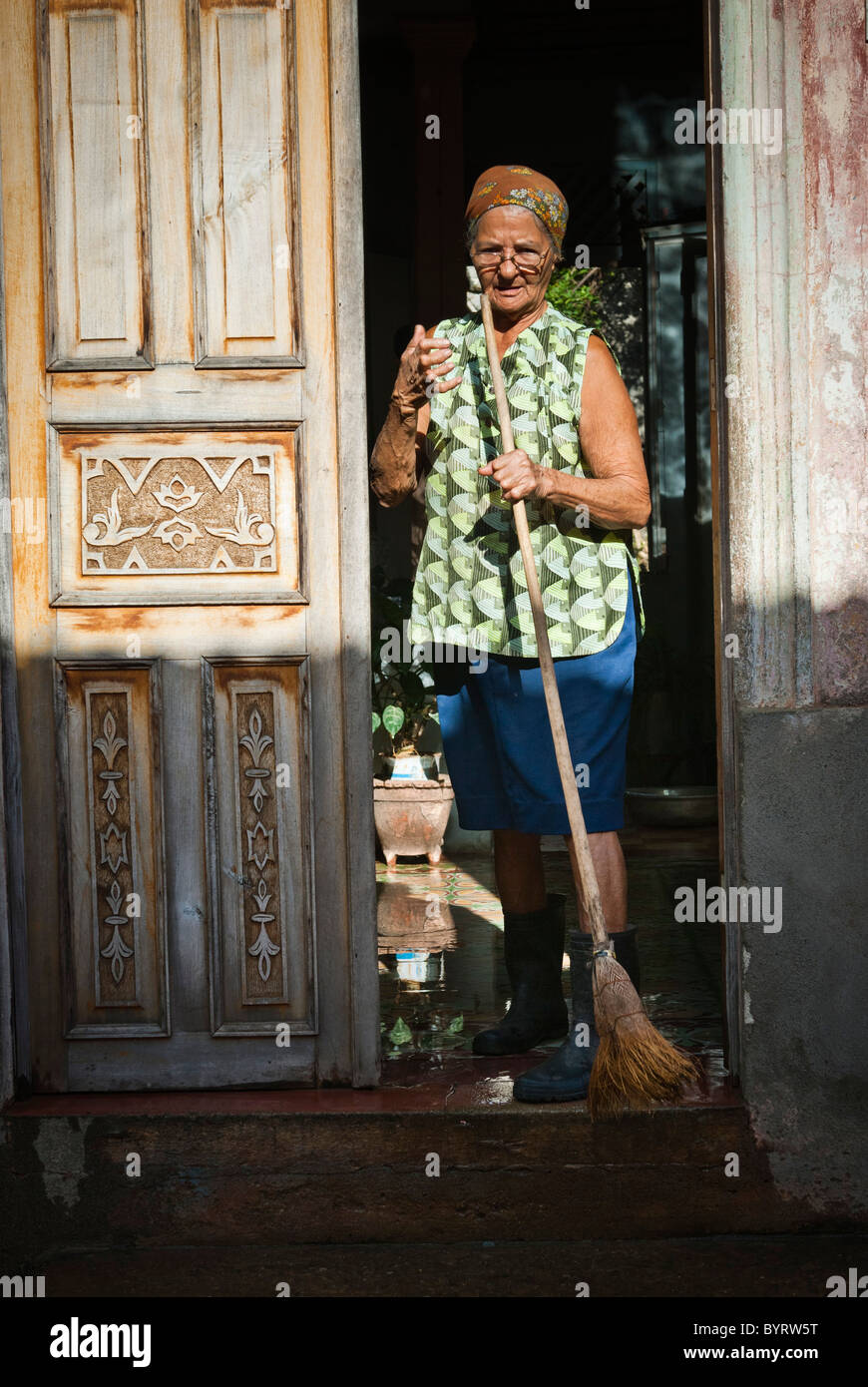 Vieille Femme balayant la rue devant sa maison, Baracoa, Guantanamo, Cuba, Caraïbes. Banque D'Images
