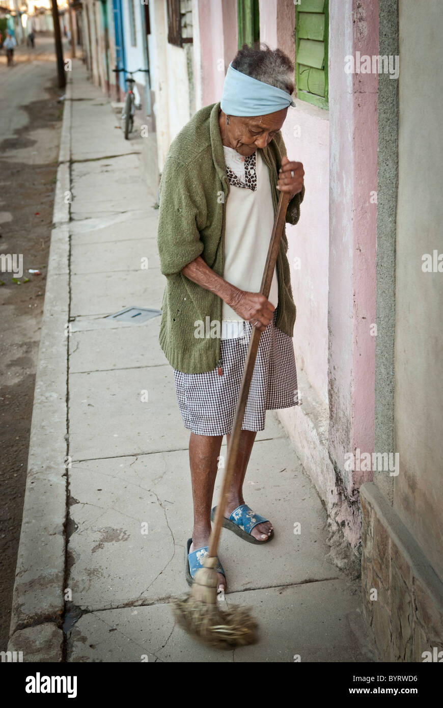 Vieille Femme balayant la rue devant sa maison, Trinidad, Sancti Spiritus, Cuba, Caraïbes. Banque D'Images