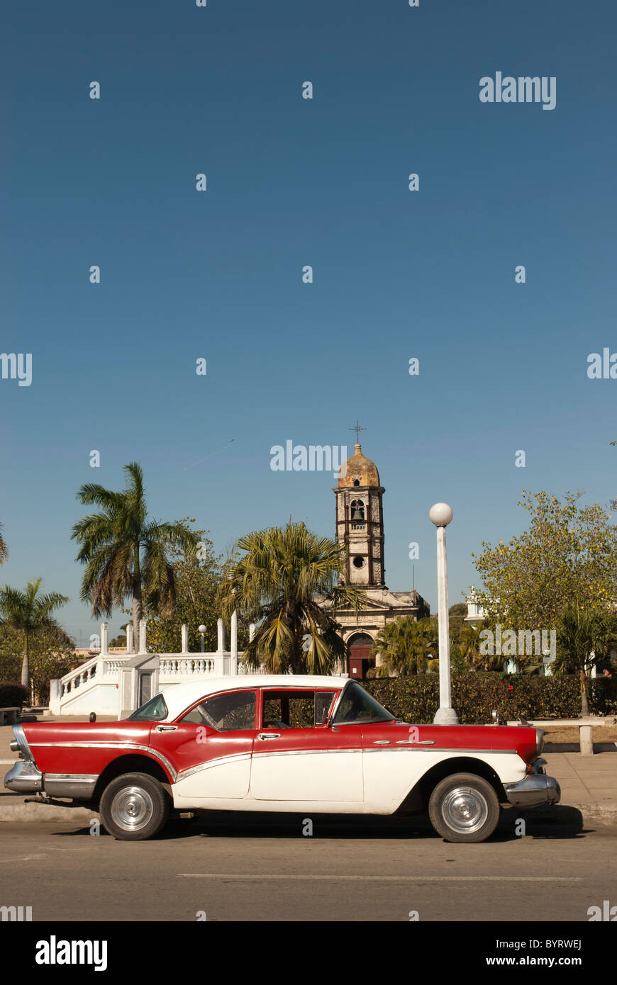 Vieille voiture sur la place de Paris avec une église catholique dans l'arrière-plan, Cienfuegos, Cuba. Banque D'Images