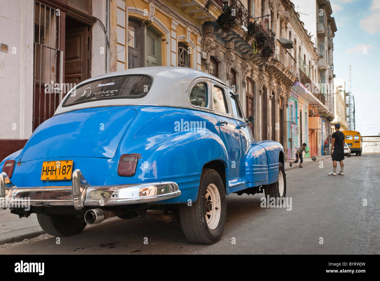 Les garçons jouent au football près d'une voiture d'époque. Ciudad de La Habana, Cuba, Caraïbes. Banque D'Images