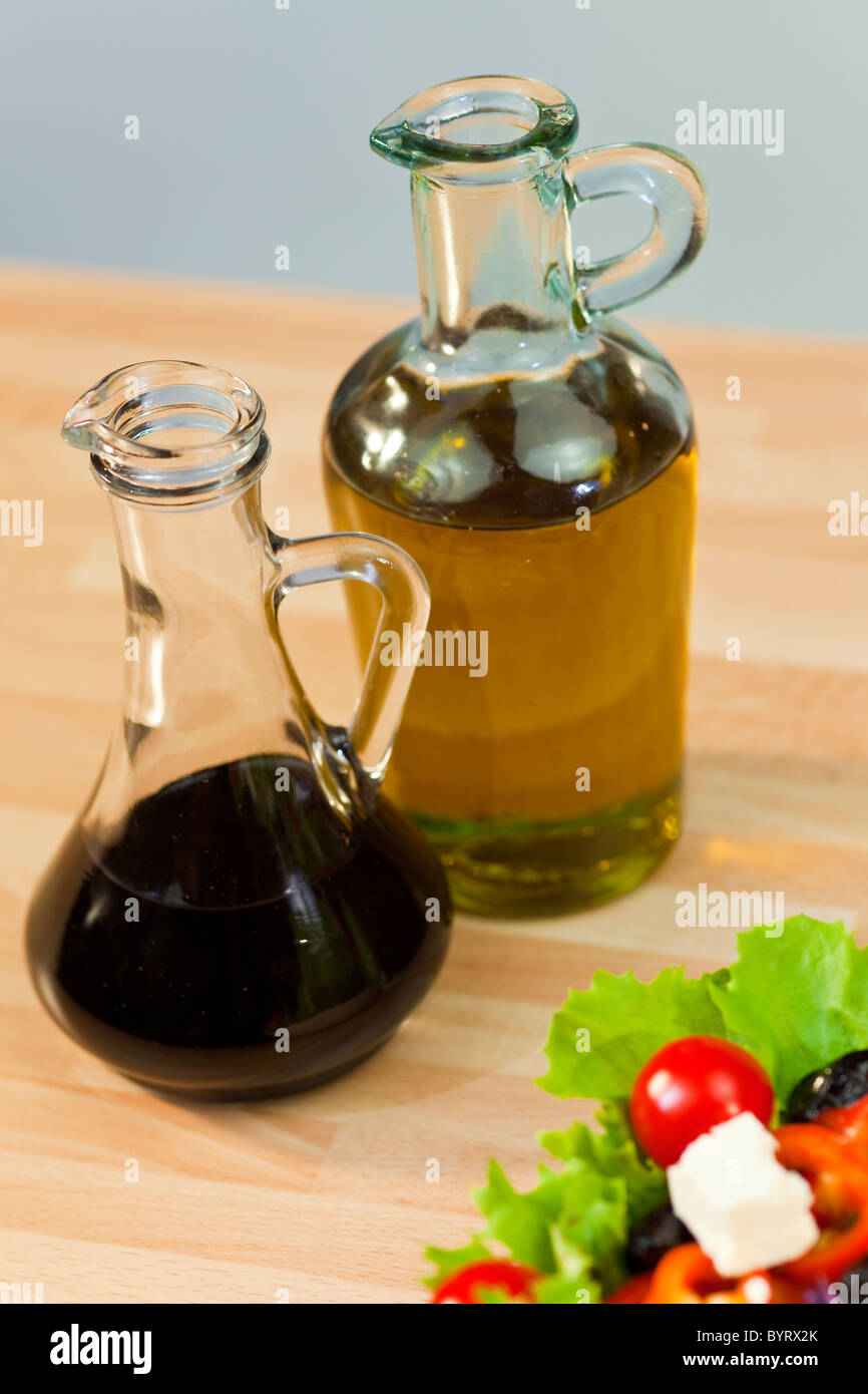 Bouteilles d'huile d'olive et de vinaigre balsamique vinaigrette avec de la laitue fraîche poivre tomates oignon rouge d'olive et salade de fromage feta Banque D'Images