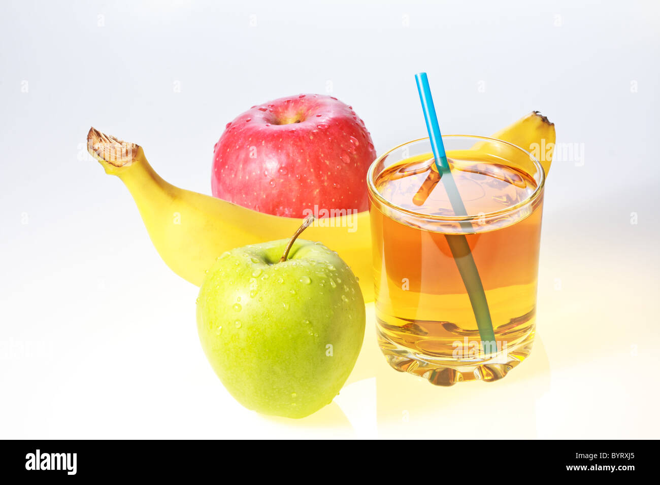 Banane, pomme verte et rouge et verre de jus de pomme avec paille Banque D'Images