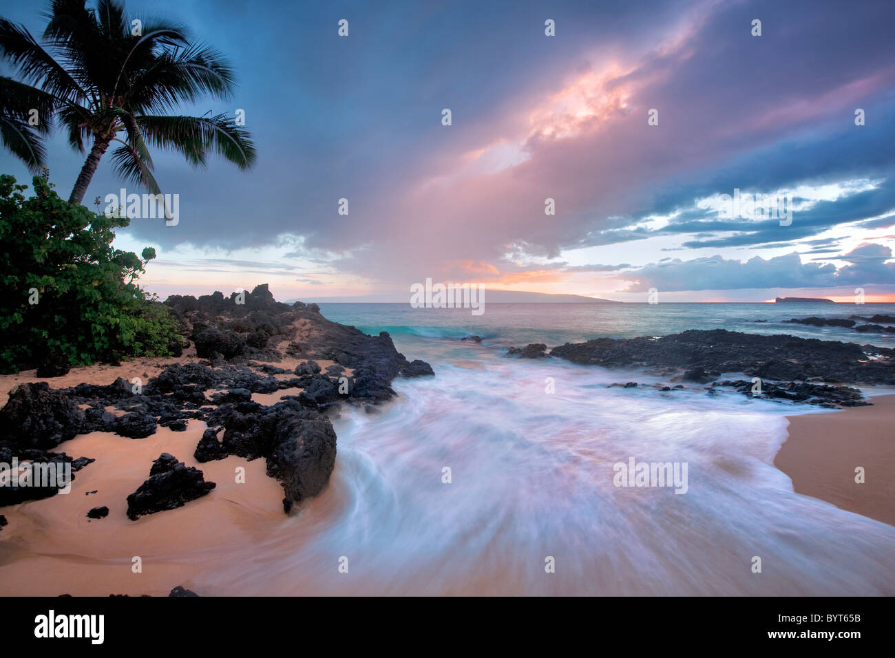 Coucher Soleil nuages et des vagues avec des palmiers. Maui, Hawaii. Banque D'Images