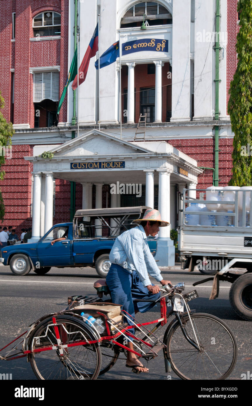 MYANMAR (BIRMANIE) MAN CYCLING COURS DES VIEUX RESTES D'ARCHITECTURE COLONIALE BRITANNIQUE AU CENTRE-VILLE DE Yangon (Rangoon) Banque D'Images