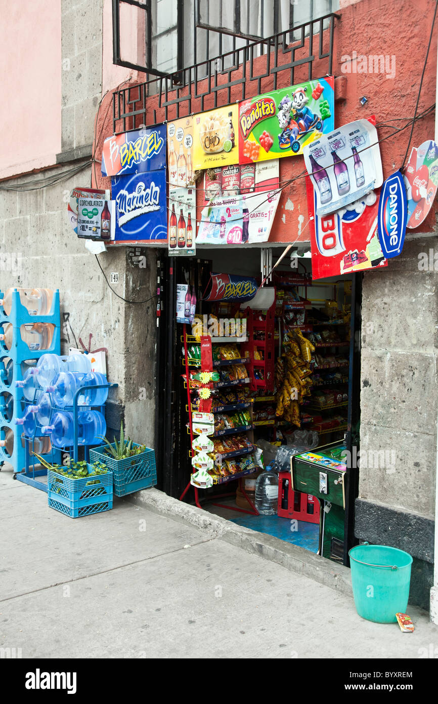 Trou dans le mur bodega la vente de malbouffe tapissés de panneaux publicitaires pour des collations sodas mexicain Mexico district Roms Banque D'Images