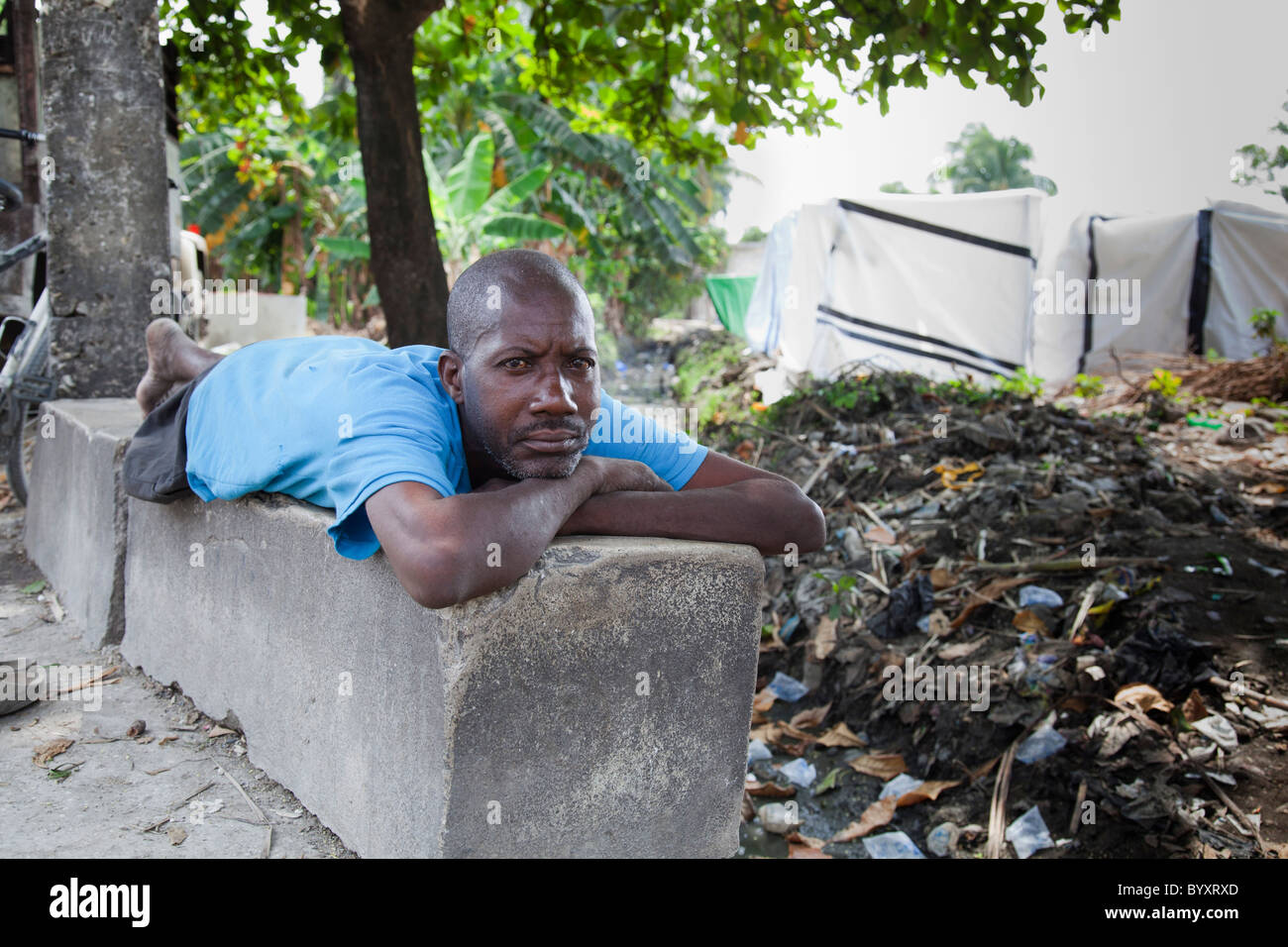 Un homme qui a tout perdu déplacées lors d'un tremblement de terre avec son camp derrière lui ; Port-au-Prince, Haïti Banque D'Images