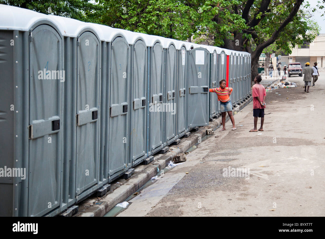 Deux enfants se tenant par une rangée de toilettes portables ; Port-au-Prince, Haïti Banque D'Images