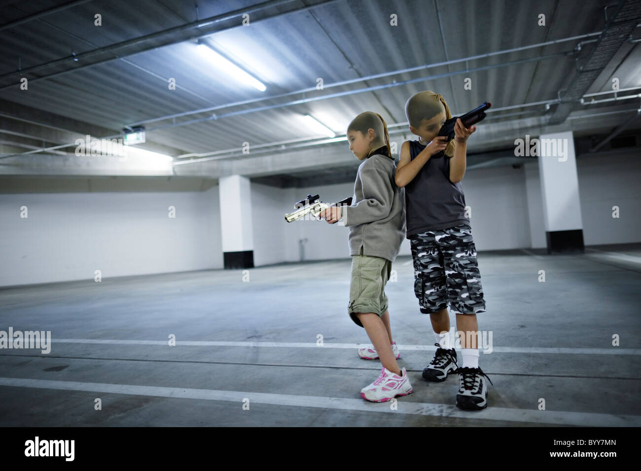 Les enfants avec les masques et les armes-jouets dans parking souterrain se préparer à grand hold-up. Banque D'Images