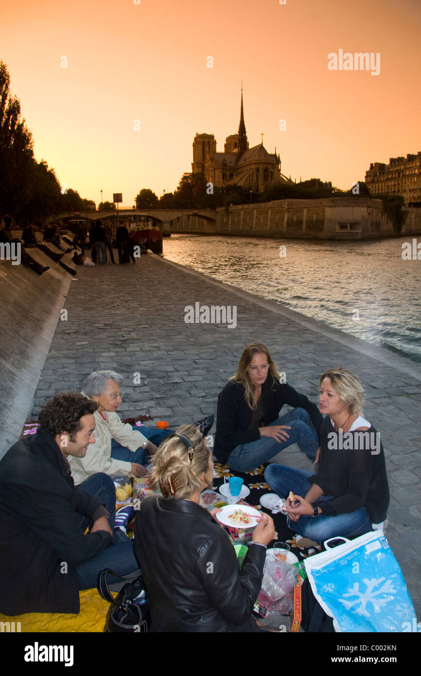 Les pique-niques parisiens le long de la Seine au coucher du soleil à Paris, France. Banque D'Images