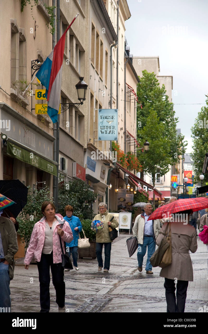 Les piétons marcher sous la pluie sur une rue piétonne dans la ville de Luxembourg, Luxembourg. Banque D'Images