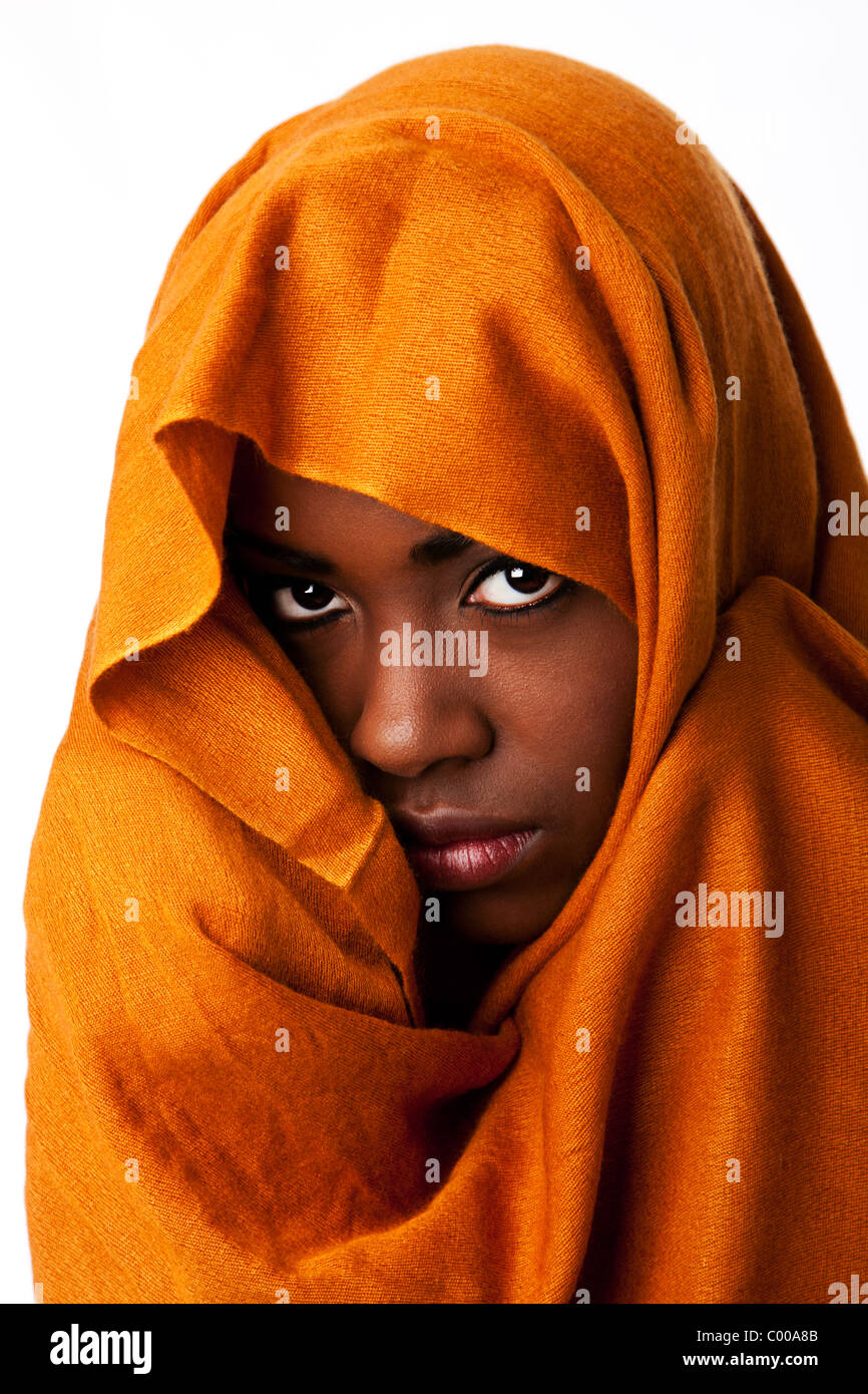 Belle africaine bédouins nomades mystérieux visage féminin dans des tons de terre ocre head wrap écharpe à la recherche. Banque D'Images