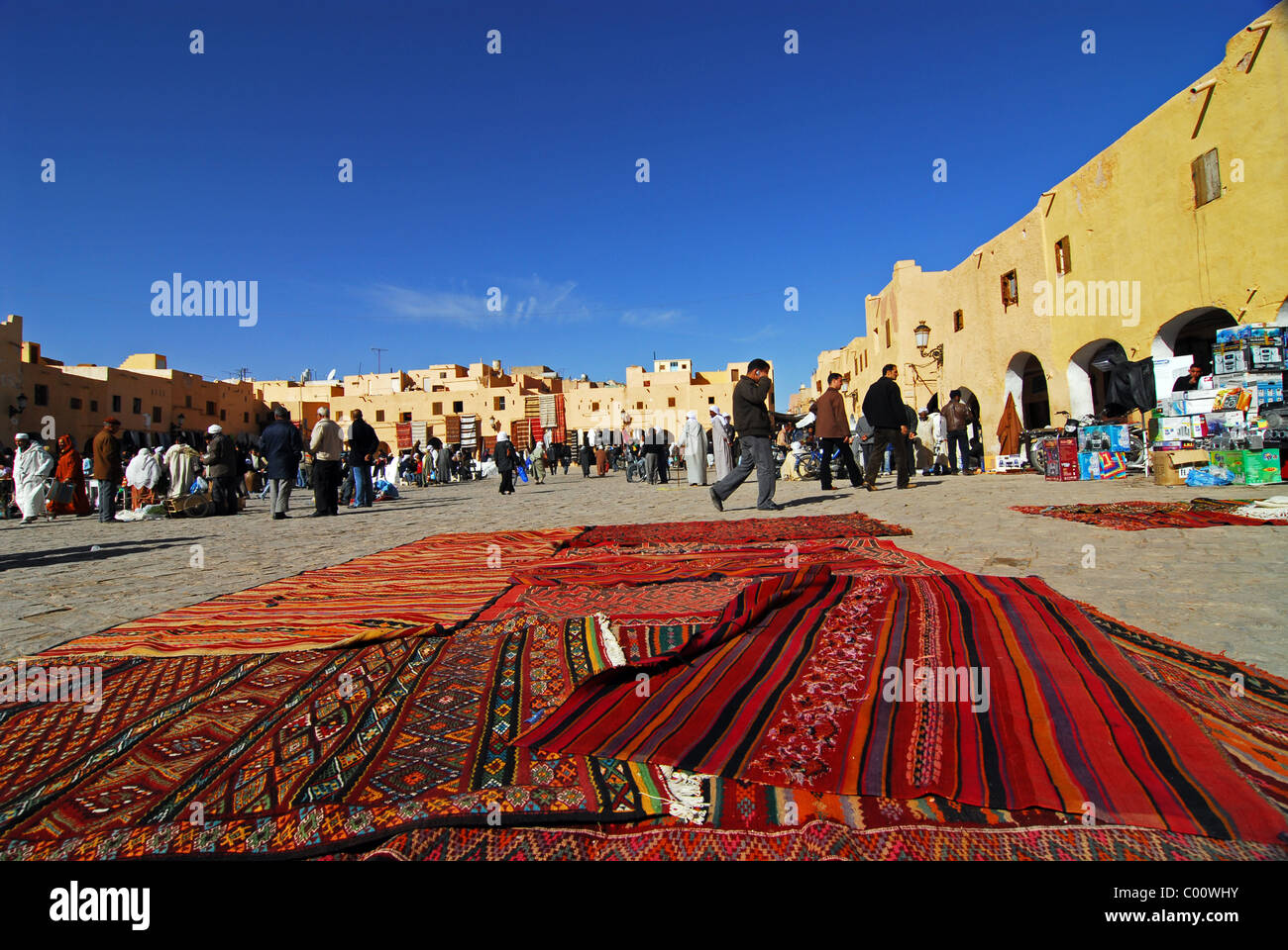 L'Algérie, Ghardaïa, les gens à la place de marché avec une variété de tapis exposés à la vente dans l'avant-plan Banque D'Images L'Algérie, Ghardaïa, les gens à la place de marché avec une variété de tapis exposés à la vente dans l'avant-plan Banque D'Images