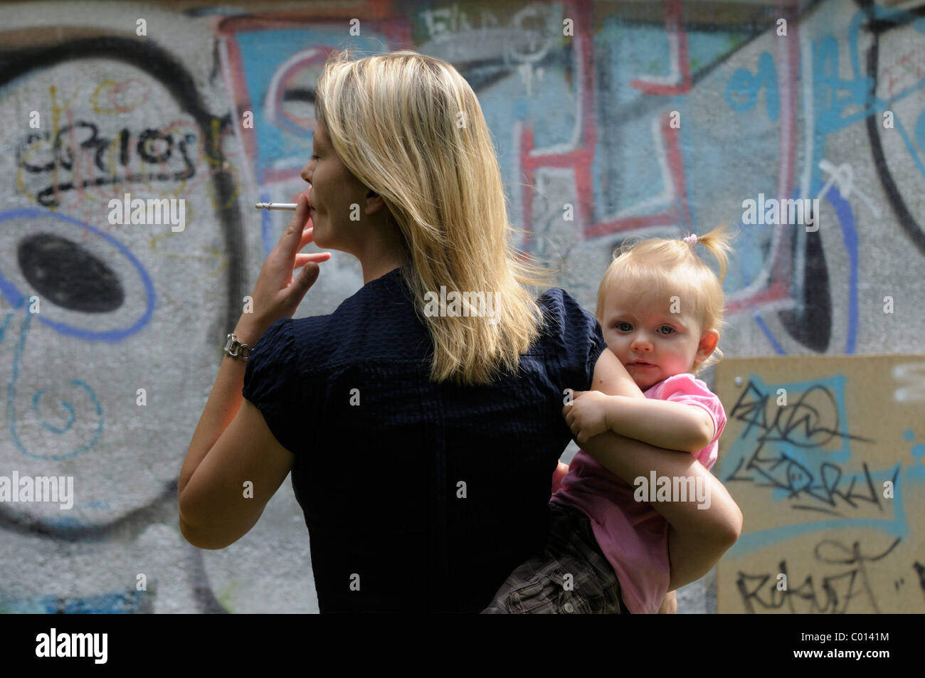 Jeune femme de fumer la cigarette, petite fille, 2 ans Banque D'Images
